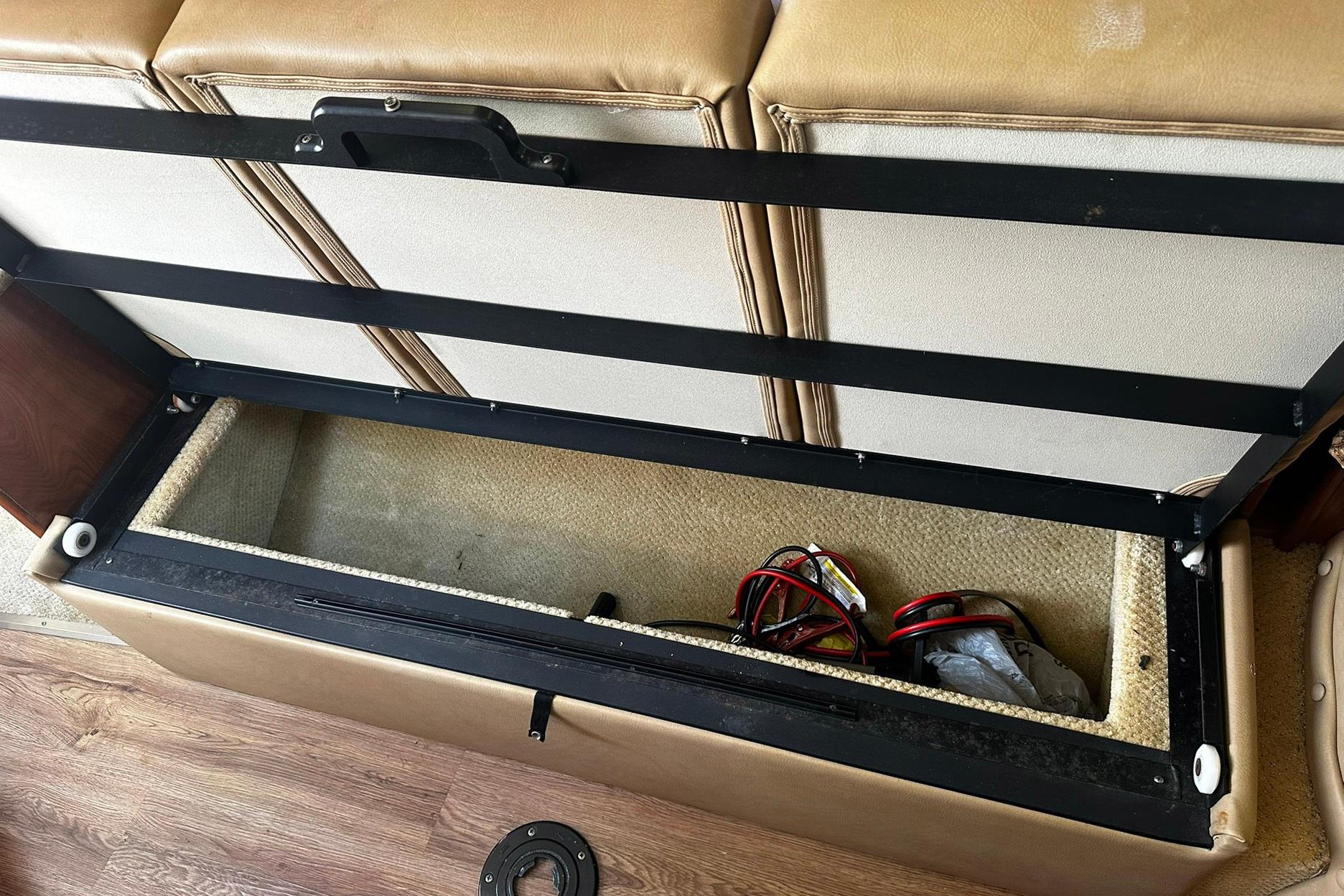 Open storage compartment in 2012 Rinker 310 Express Cruiser LE boat, showing cables inside.