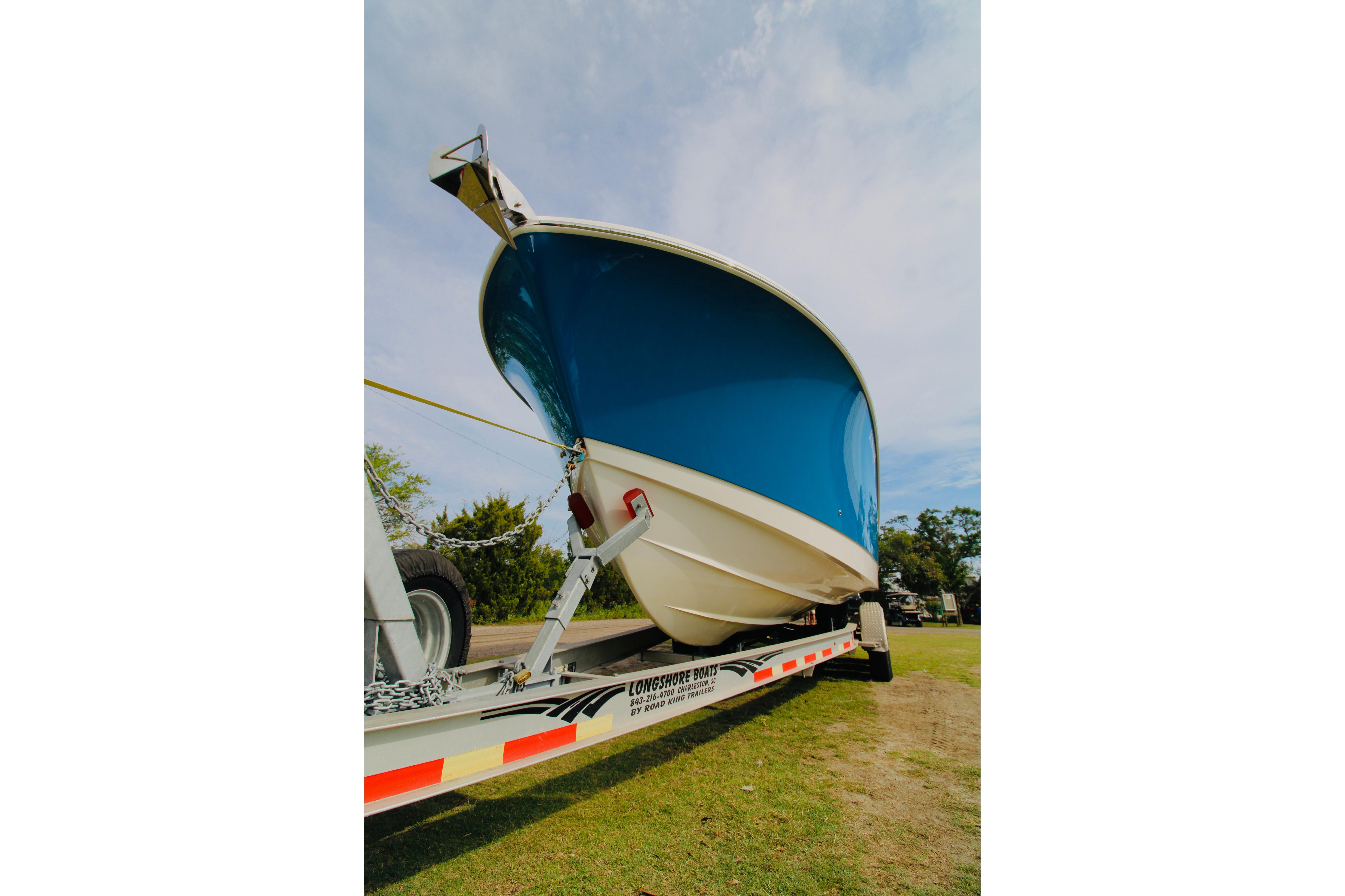 2022 Edgewater 280CC boat on trailer, blue hull, parked on grass under clear sky.