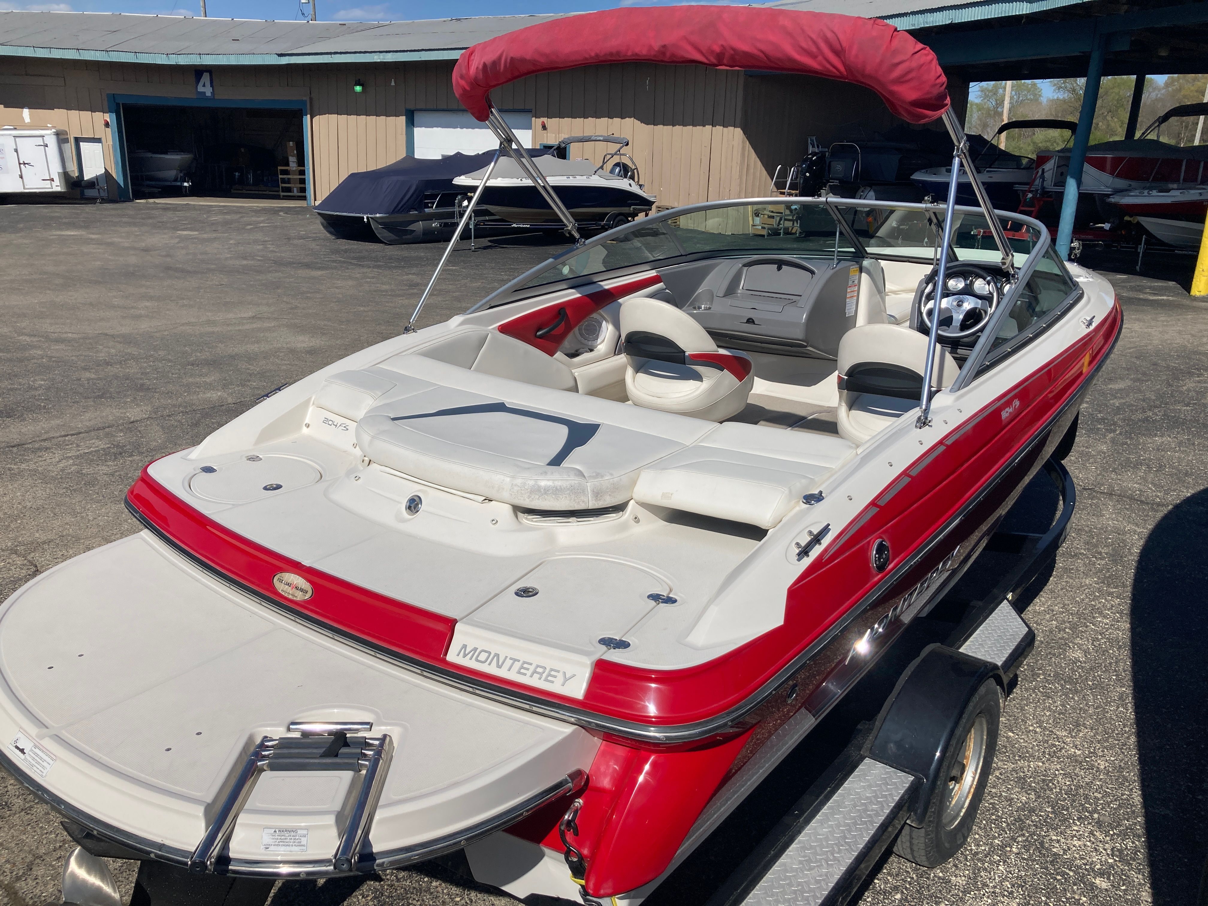 2012 Monterey 204FS boat with red canopy on trailer.
