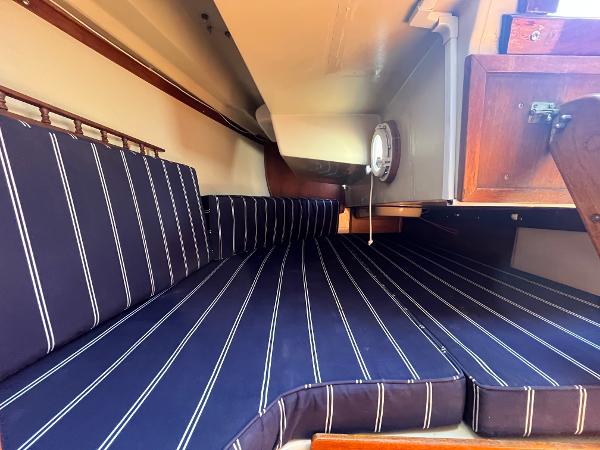Interior cabin of 1980 Catalina 30 sailboat with striped cushions and wooden accents.