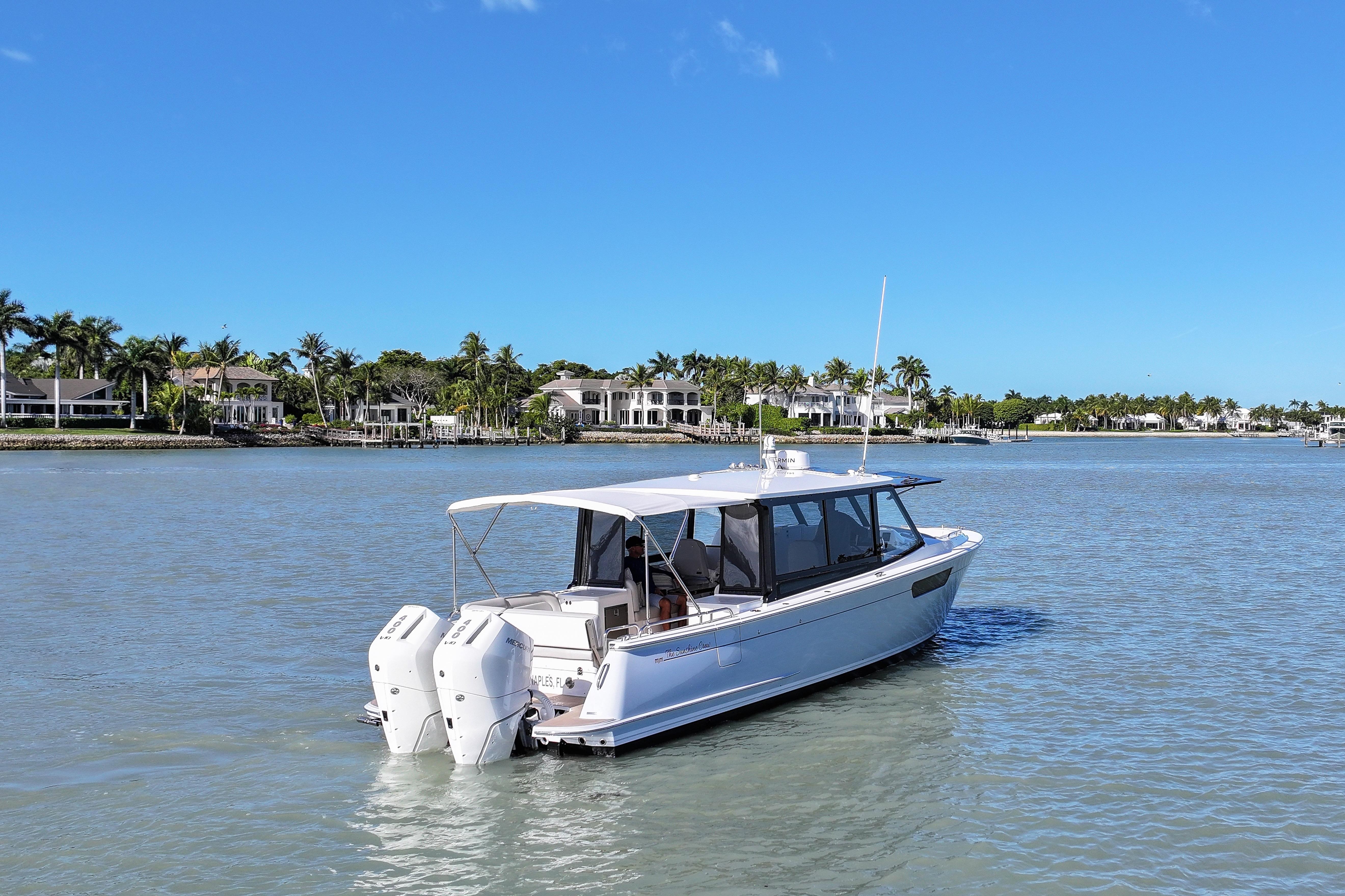2025 MJM 38 X boat on calm water with luxury homes in the background.