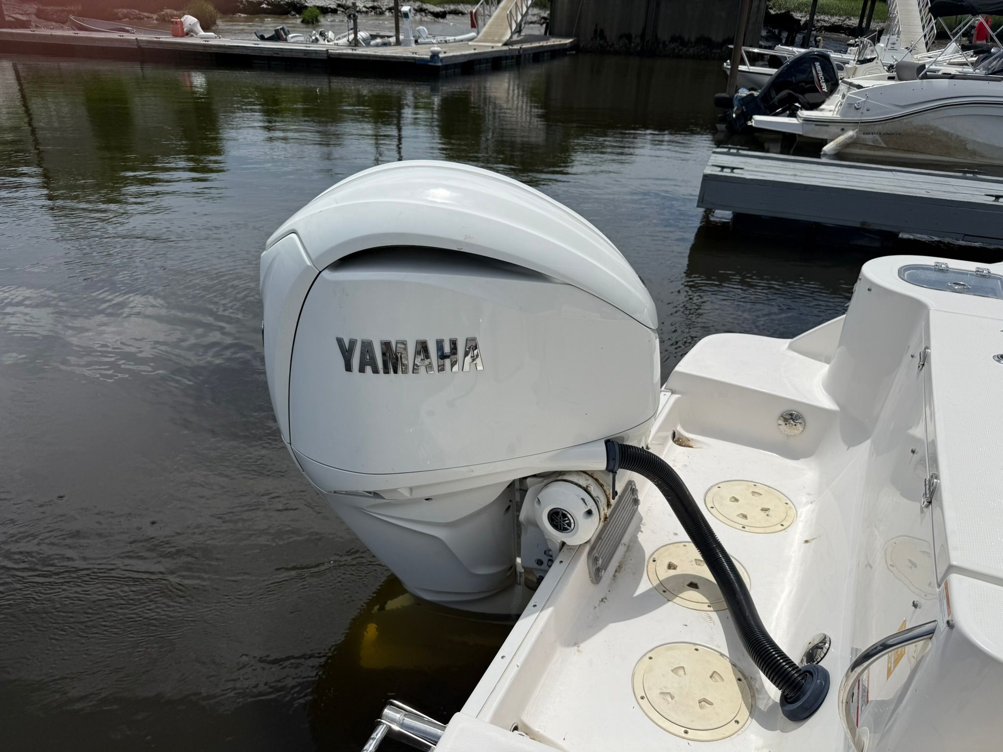 A Yamaha outboard motor on a boat in the water, surrounded by other boats at the dock.