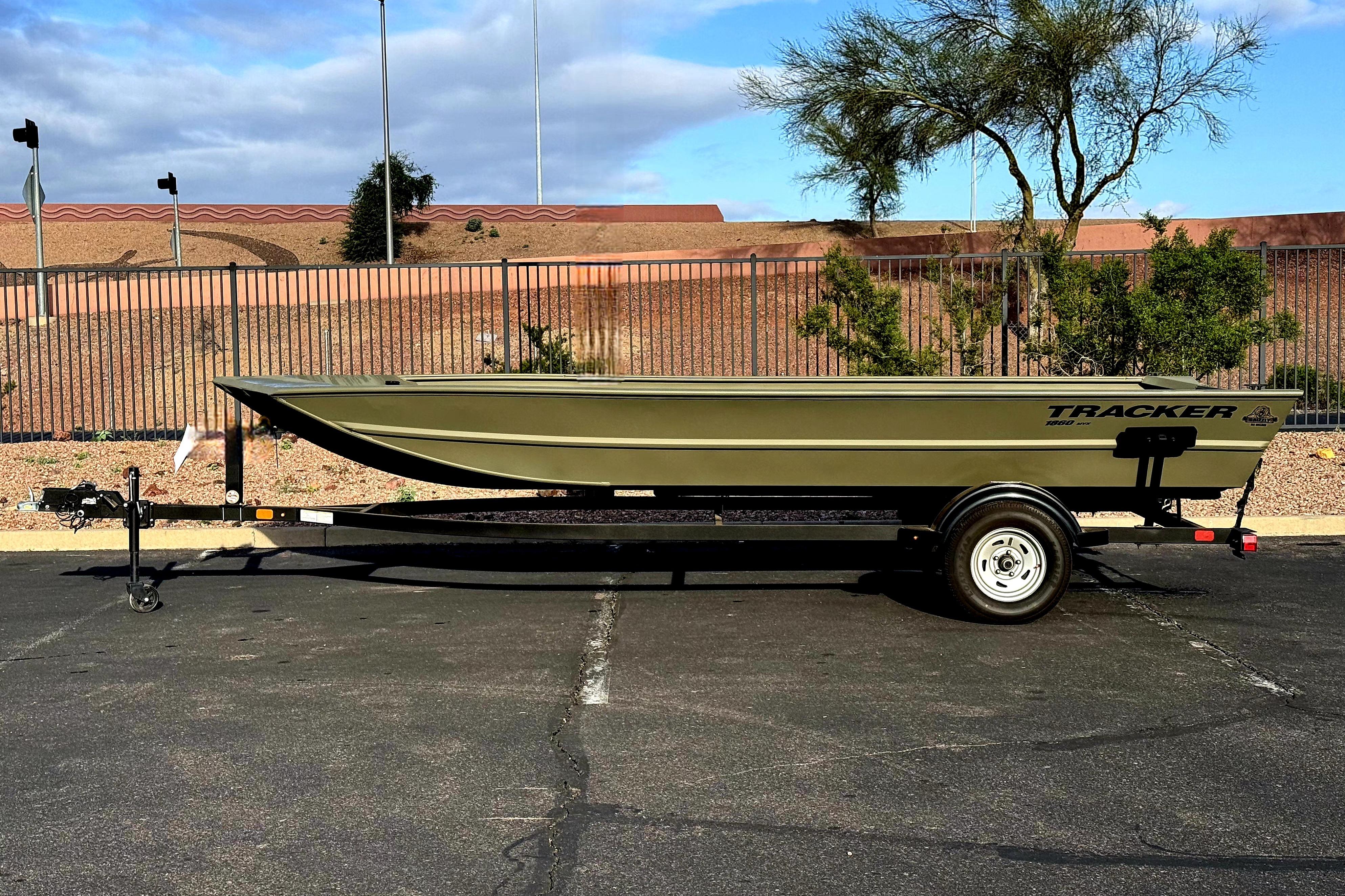 2026 Tracker Grizzly 15 Jon boat on trailer, parked outdoors under a cloudy sky.