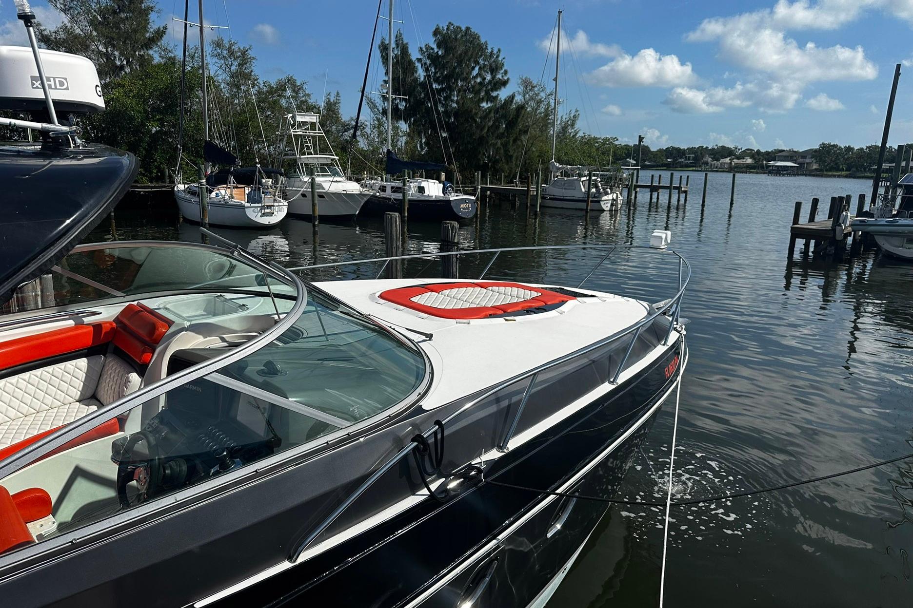 2012 Rinker 310 Express Cruiser LE docked at a marina, surrounded by sailboats.