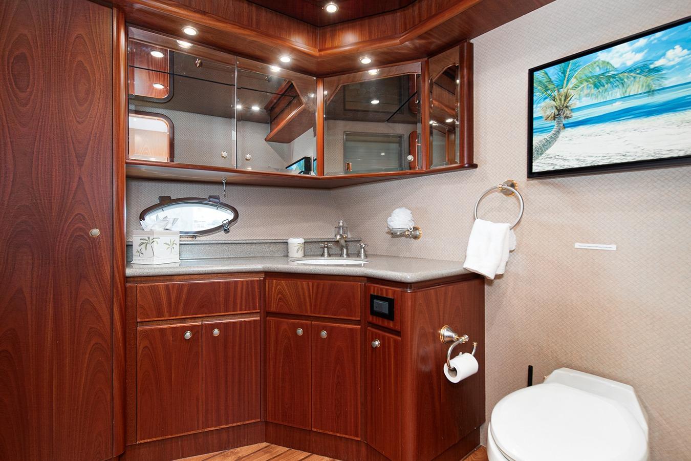 Luxurious 2003 West Bay Sonship yacht bathroom with wood cabinetry and beach artwork.