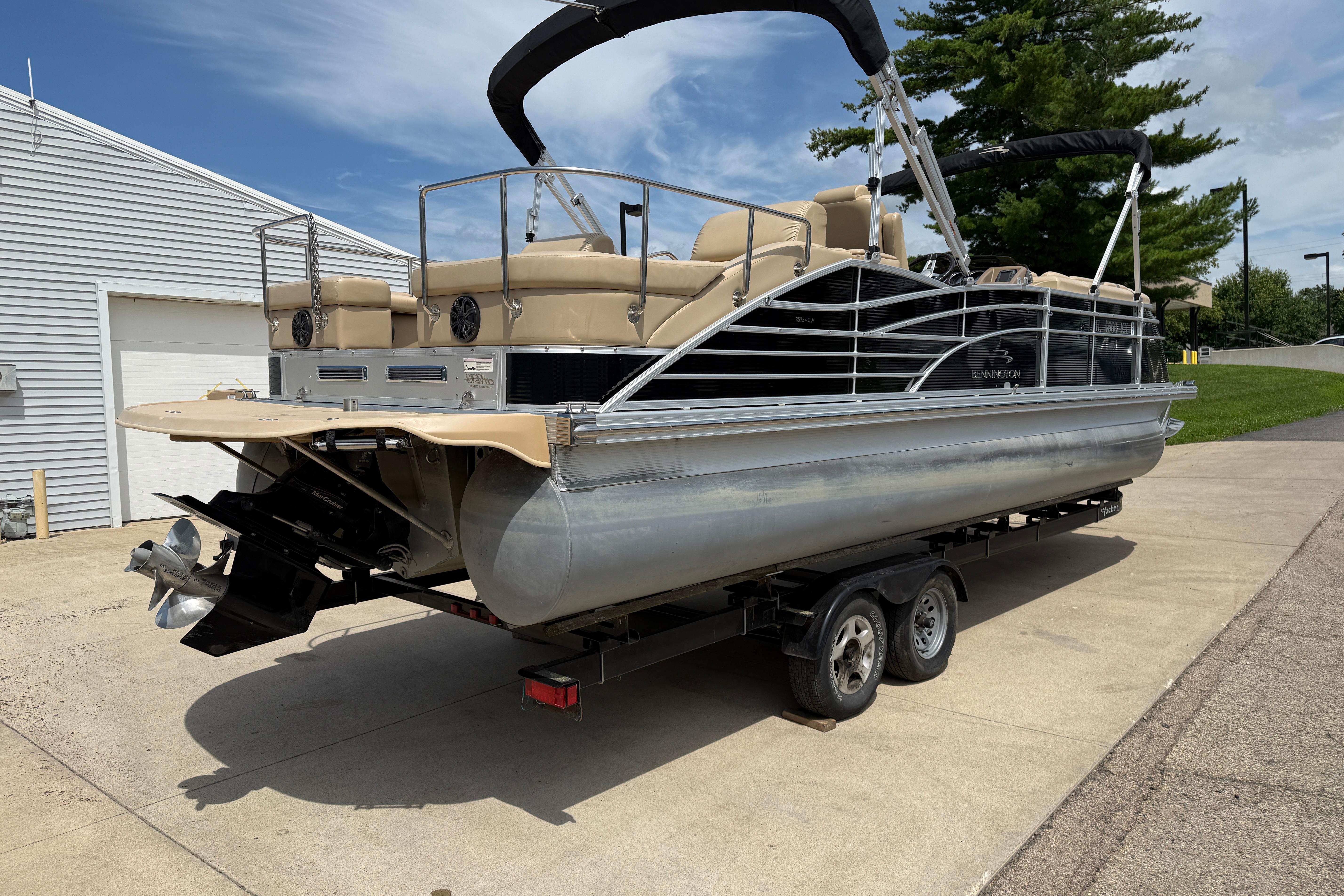 2011 Bennington 2575QCW I/O pontoon boat on trailer, parked outdoors.