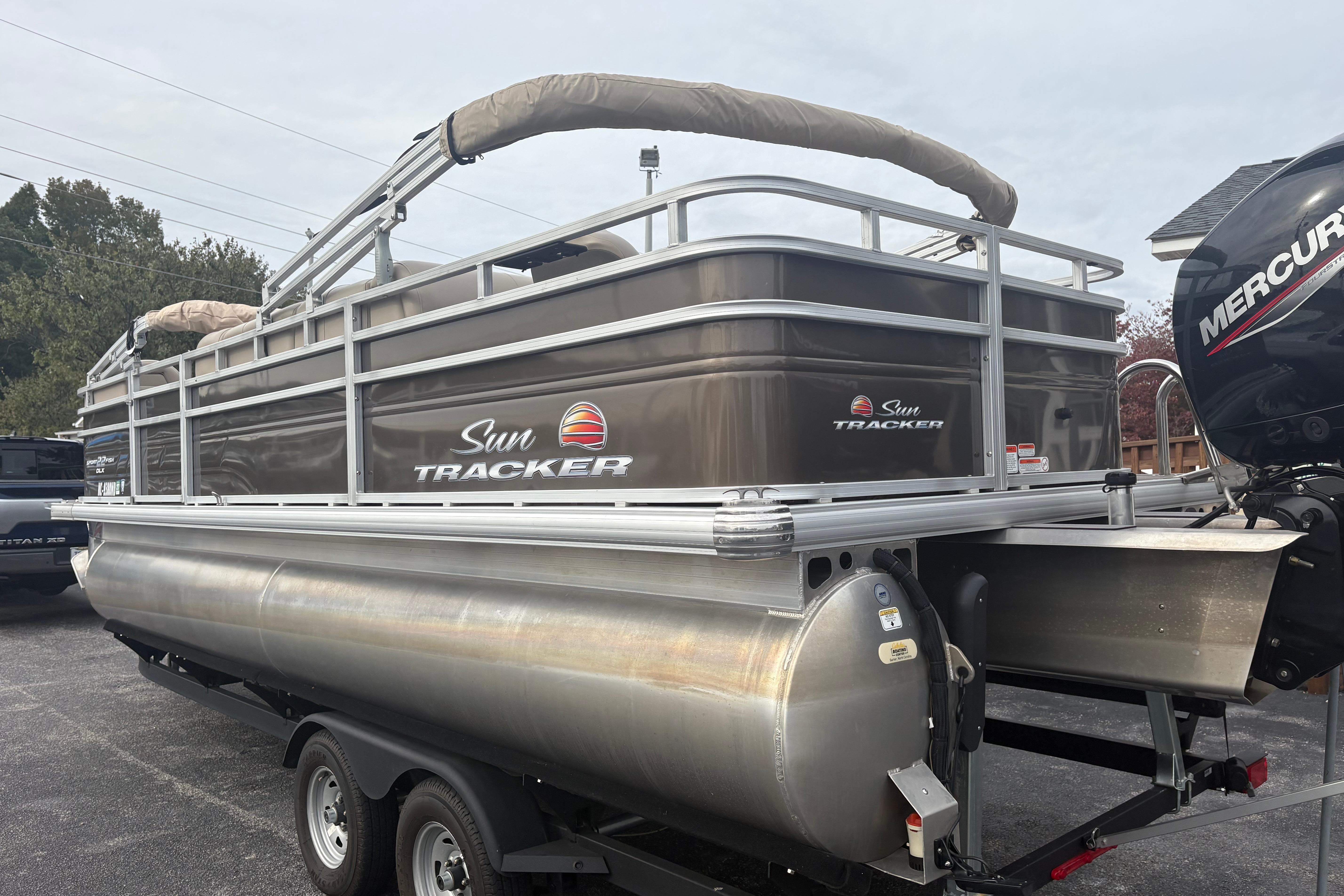 2024 Sun Tracker SportFish 22 DLX pontoon boat on trailer, featuring Mercury outboard motor.