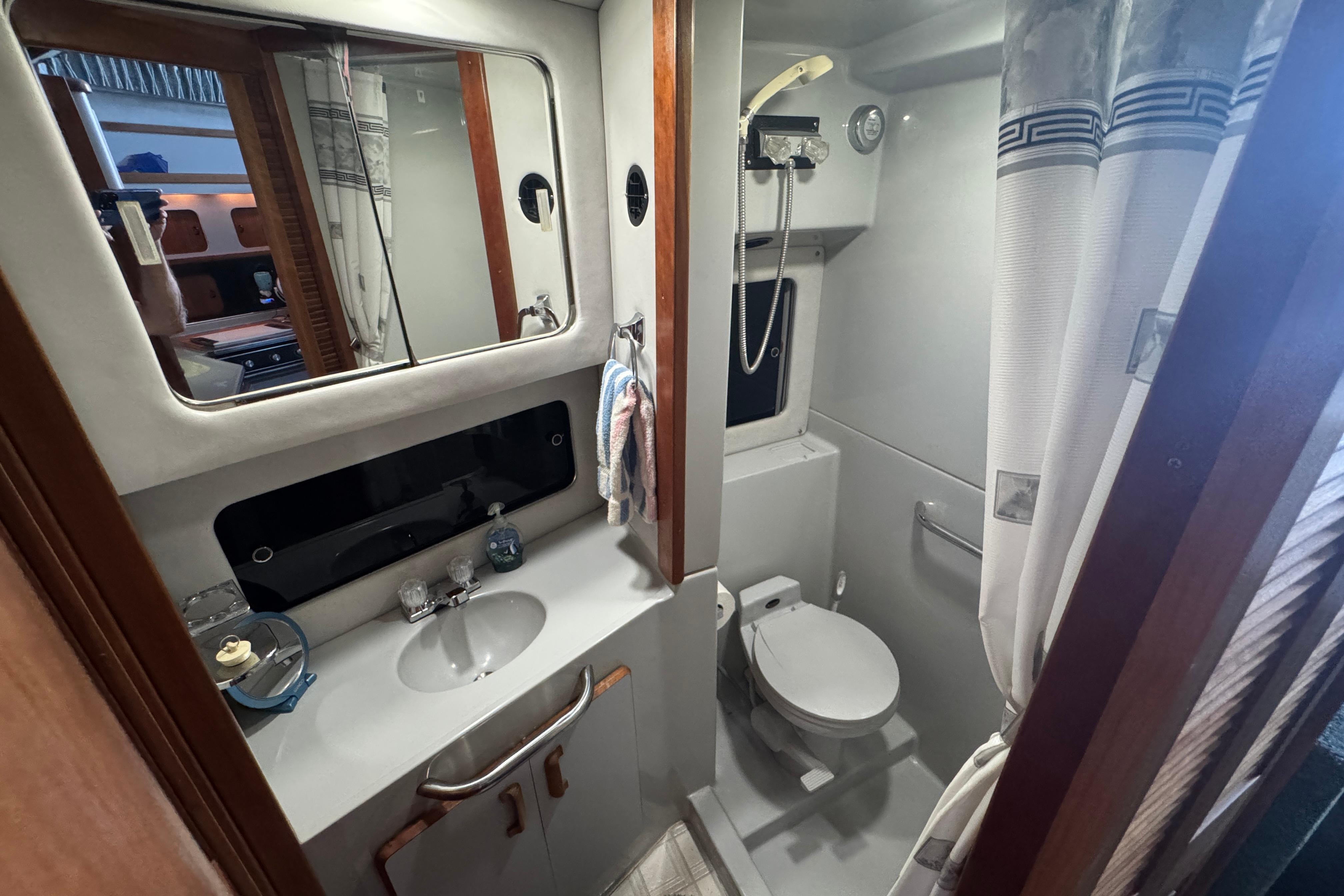1990 Sea Ray 380 Aft Cabin bathroom with sink, mirror, and shower.