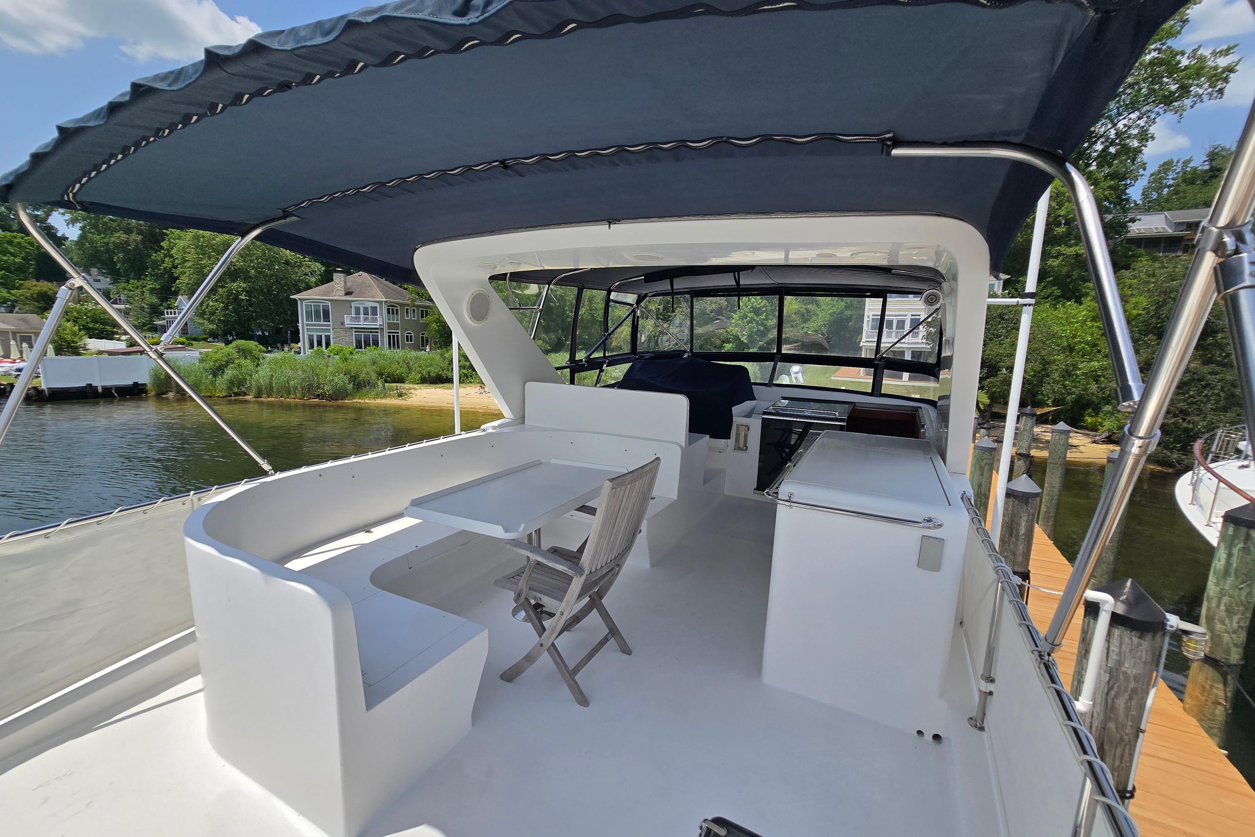 2004 Grand Harbour 58 yacht deck with seating and canopy, docked by a scenic waterfront.