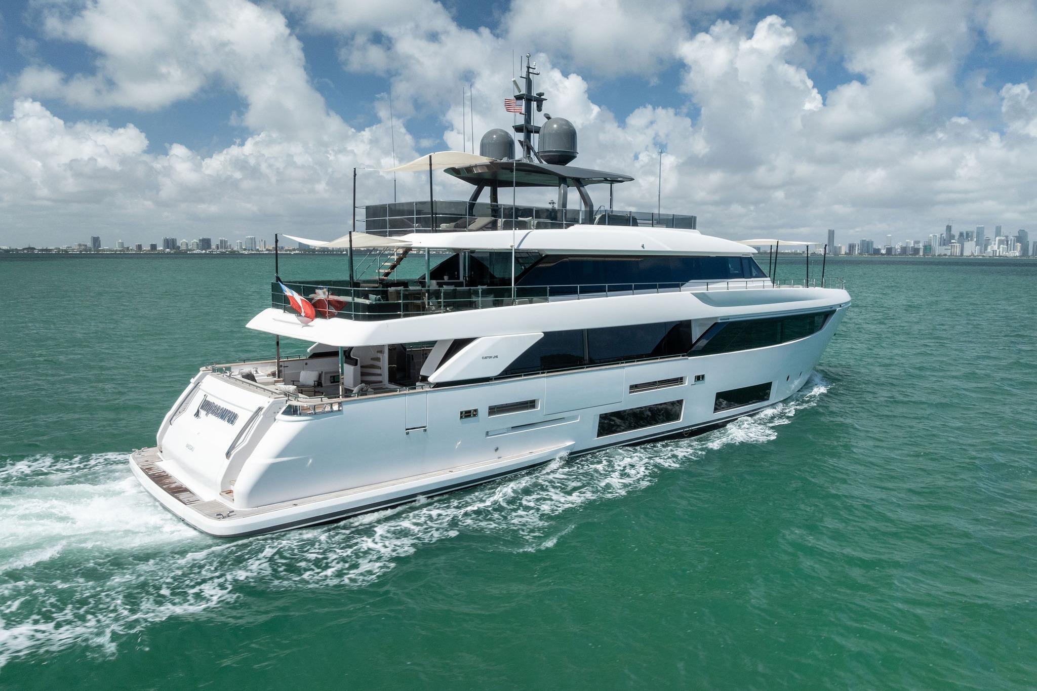 Luxurious 2023 Custom Line Navetta 33 yacht cruising on turquoise waters under a cloudy sky.