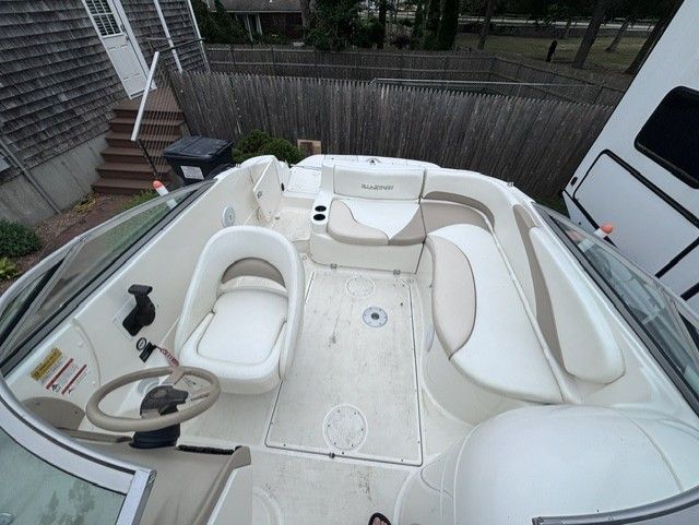 The image shows the cockpit of a 2003 Glastron DX 235 boat with white seating.