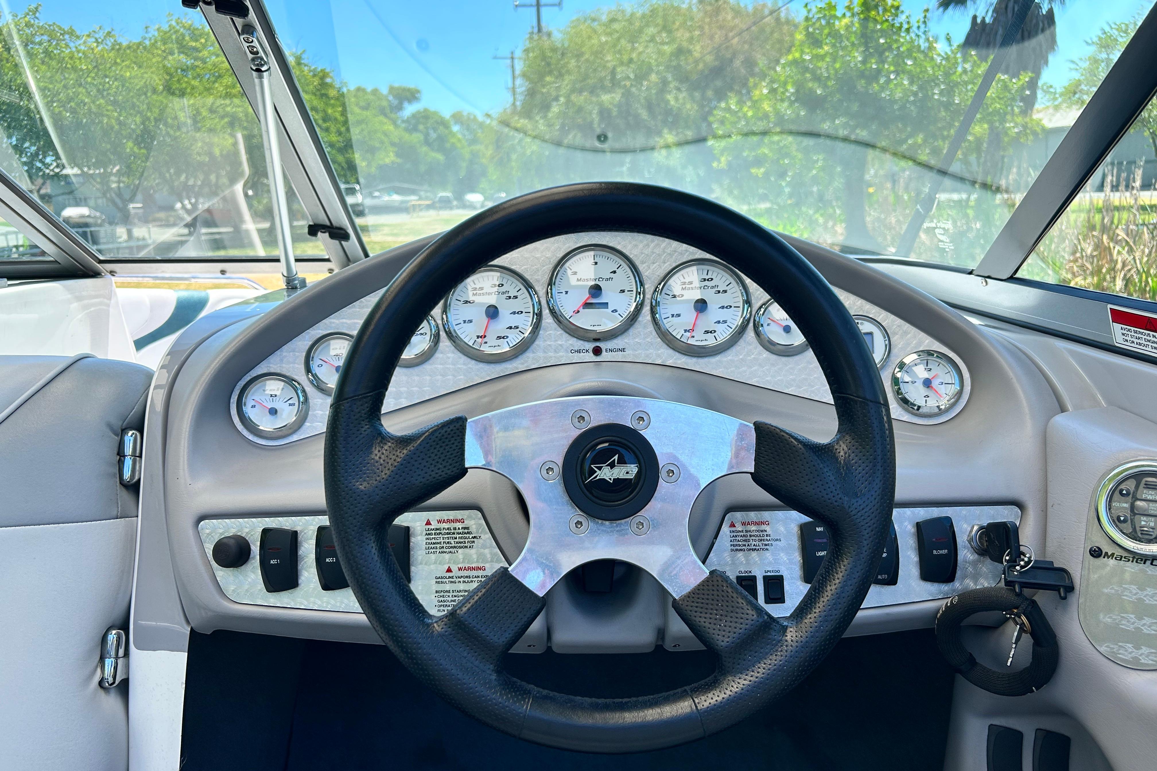 Steering wheel and dashboard of a 2002 MasterCraft ProStar 197 boat, featuring multiple gauges.