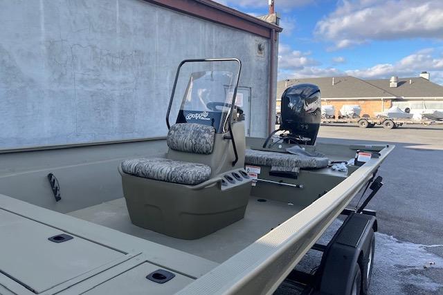2026 Tracker Grizzly 2072 CC boat with camouflage seating, parked outdoors.