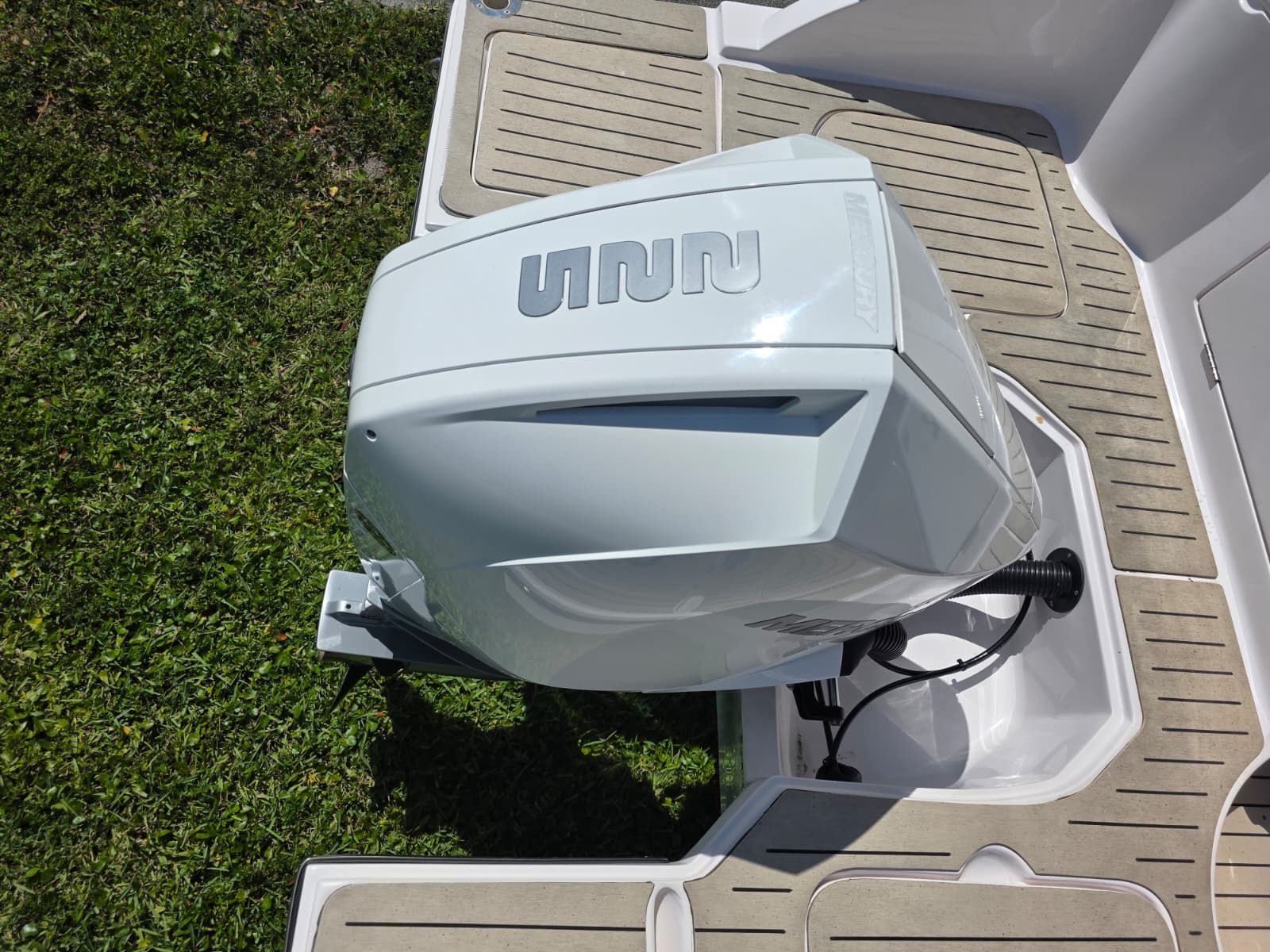 A modern outboard motor on a boat, surrounded by green grass.