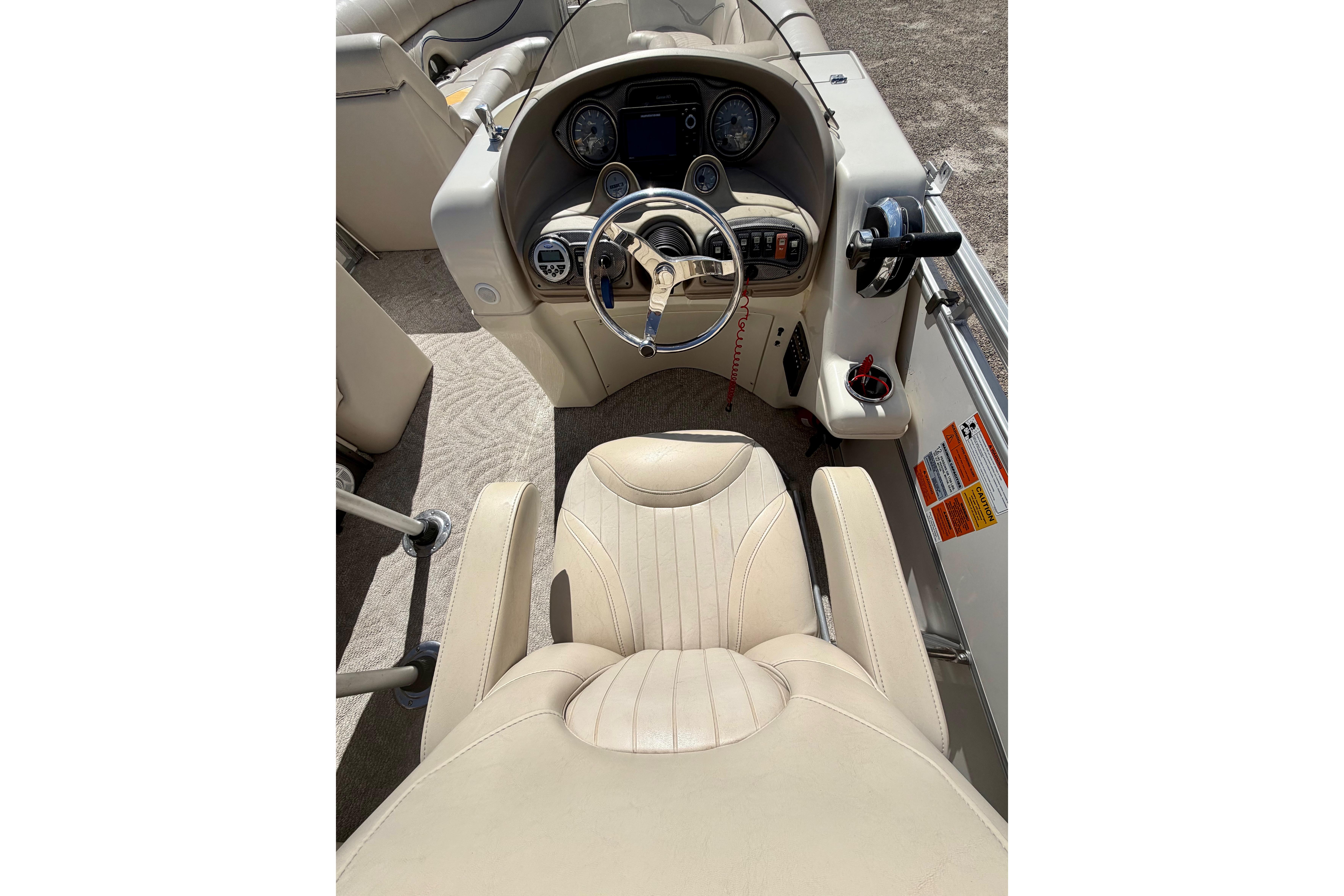 Captain's seat and helm of 2006 South Bay 925CR pontoon boat, featuring beige upholstery.