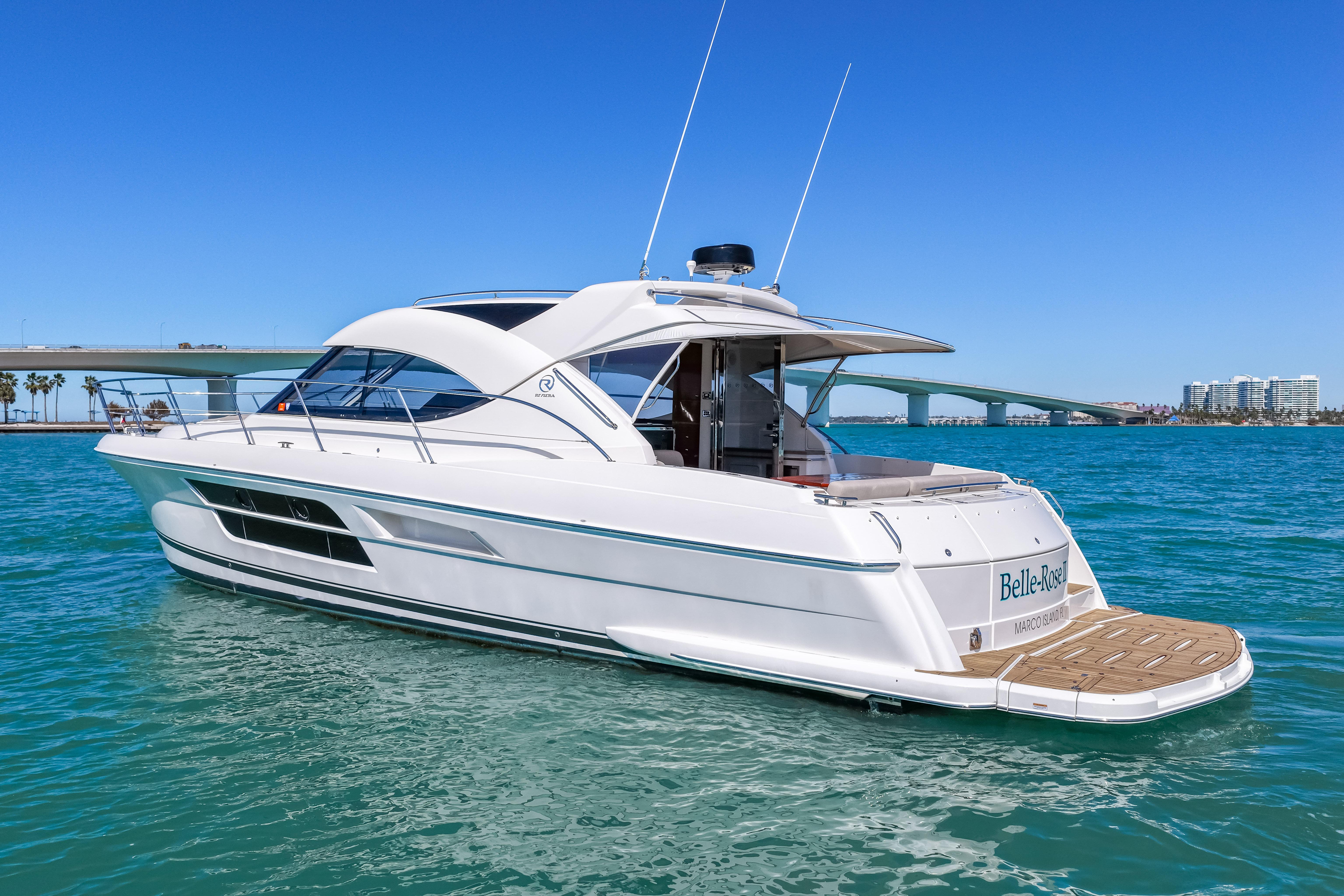 2016 Riviera 5000 Sport Yacht on clear blue water, bridge and cityscape in background.