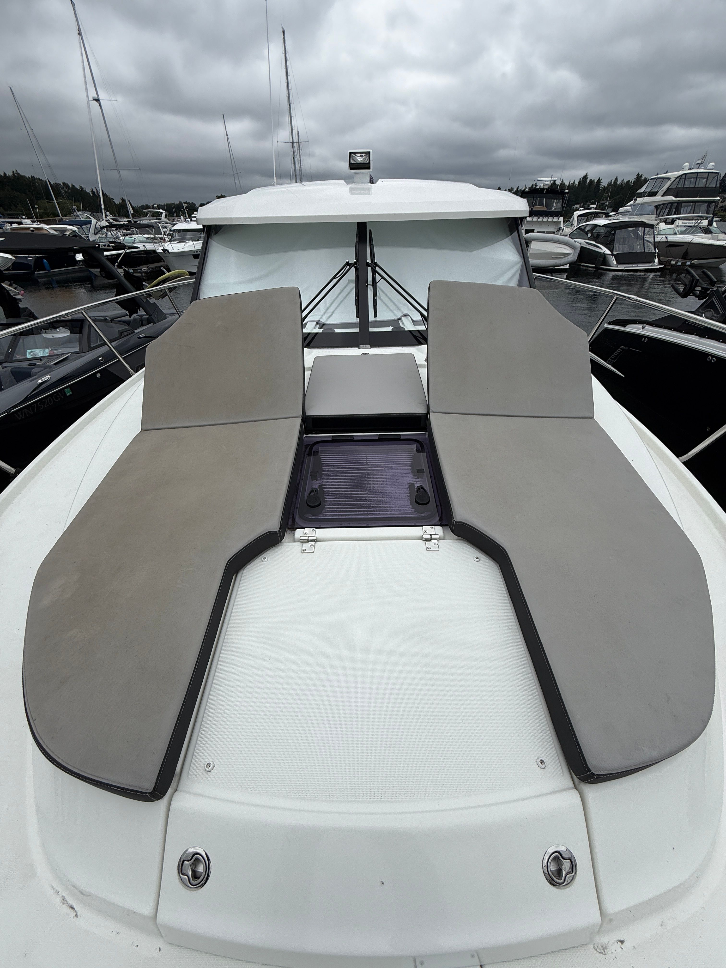 The boat features a modern design with cushioned sun pads on the deck.