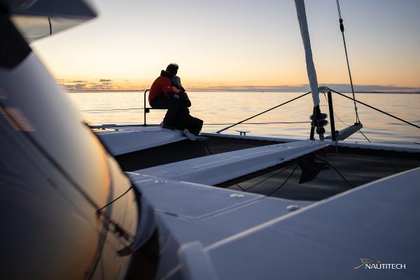 Couple enjoying sunset on Nautitech 48 Open catamaran, 2025 model, serene ocean view.