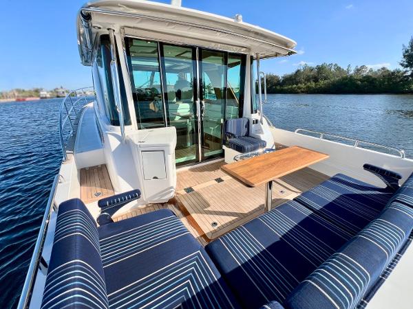 2025 Sabre 43 Salon Express yacht with outdoor seating and table on calm water.