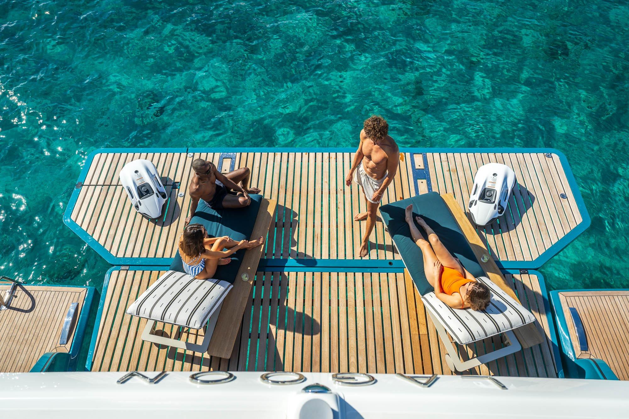 People relaxing on Lagoon Eighty 2 yacht deck, 2026, with clear blue water.