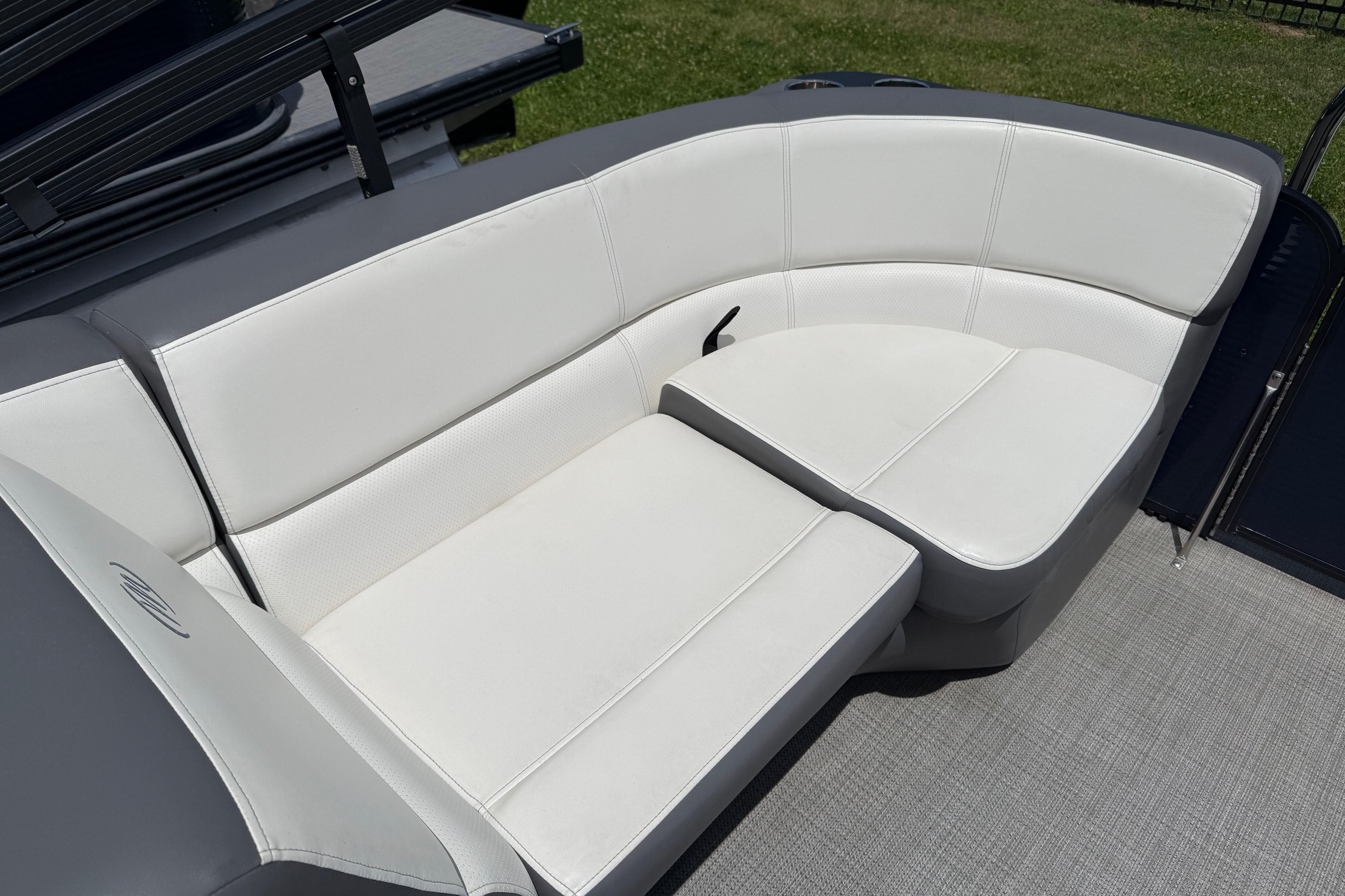 2022 Manitou Aurora LE boat with white cushioned seating on deck.