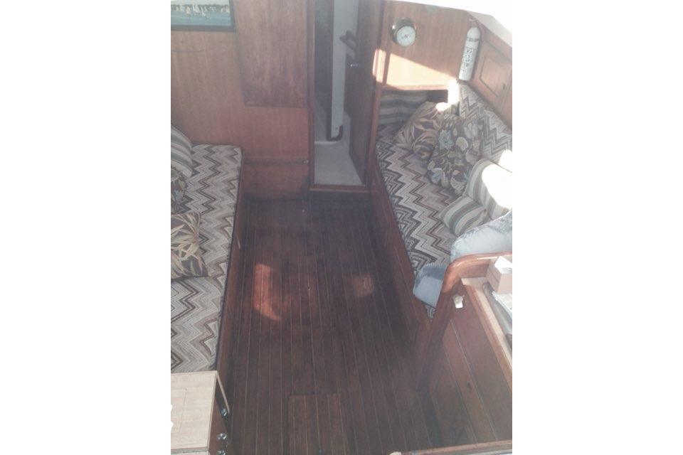 Interior of 1980 Sloop 27.7 Bristol sailboat with wooden flooring and patterned cushions.