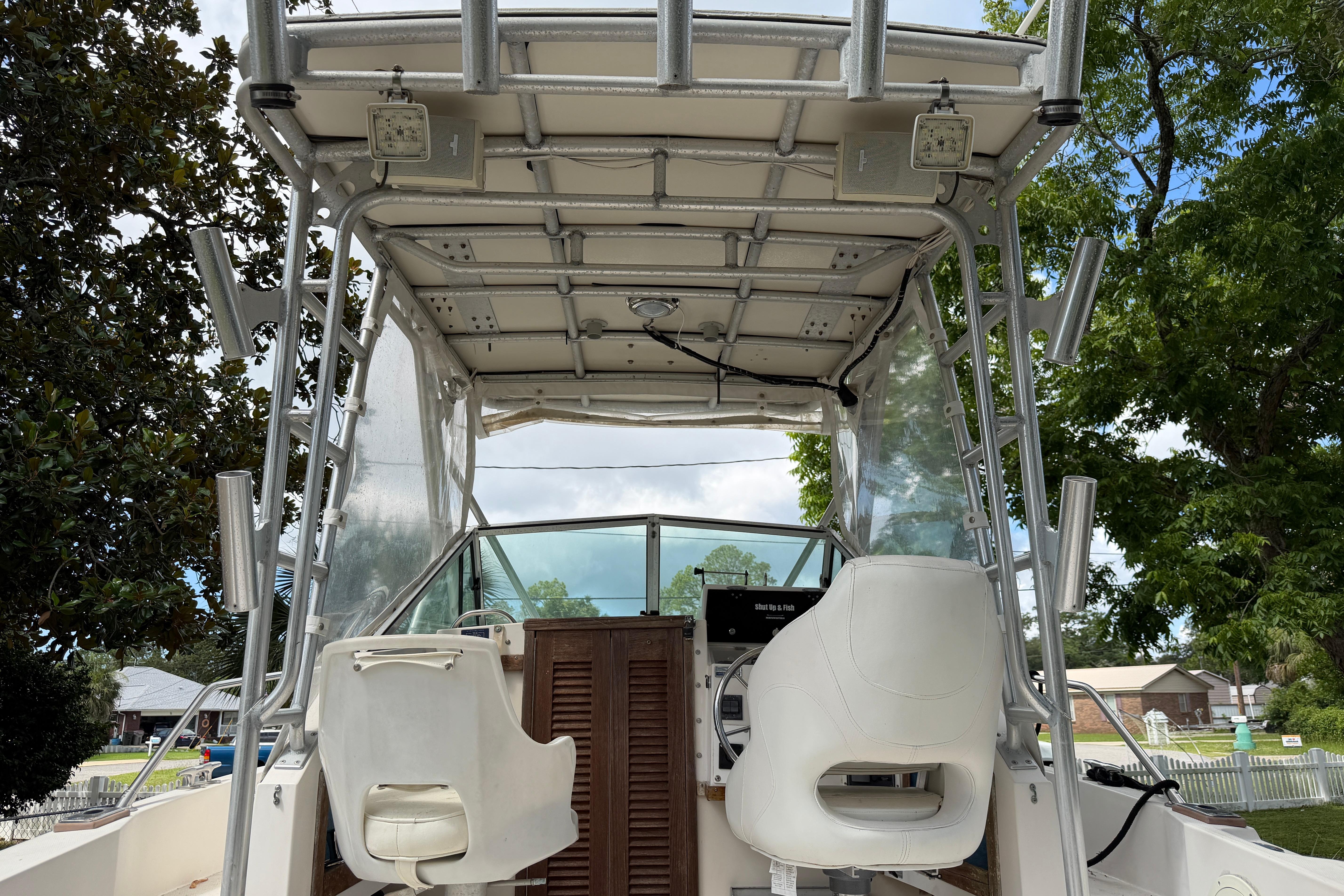 1987 Grady-White Seafarer 226 boat interior with helm seats and canopy, surrounded by trees.