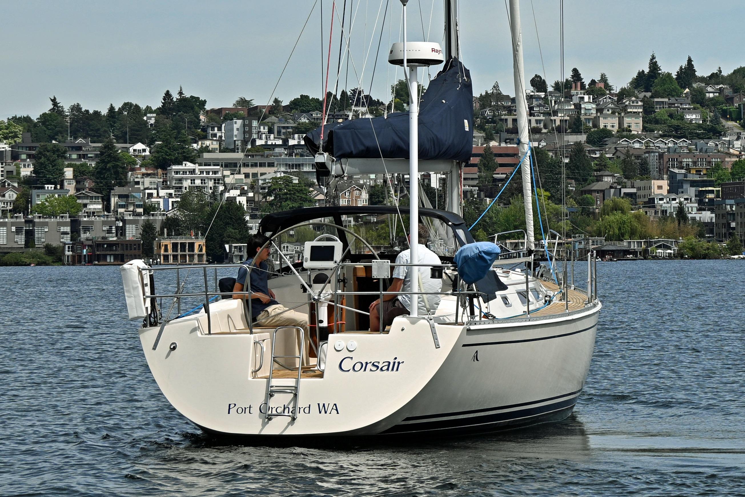 2004 Hanse 411 sailboat "Corsair" on water near Port Orchard, WA, with cityscape backdrop.