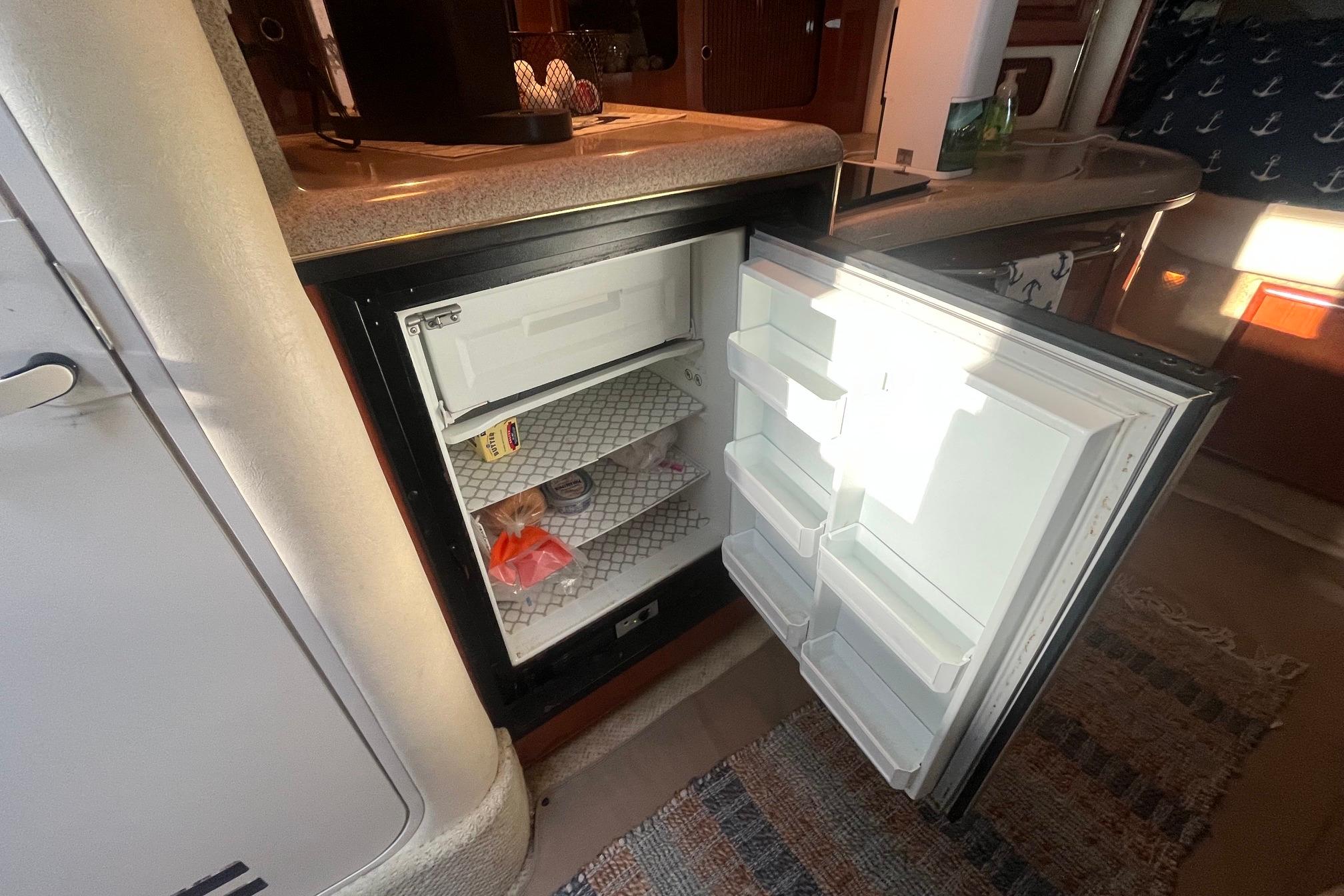 Open refrigerator inside 2001 Sea Ray 340 Sundancer yacht, showcasing interior storage space.