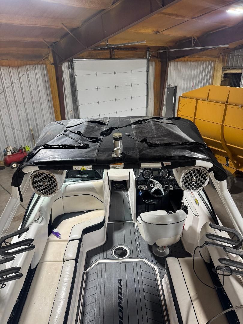 Interior view of a 2015 Moomba Mojo with white seats and black cover in a garage.