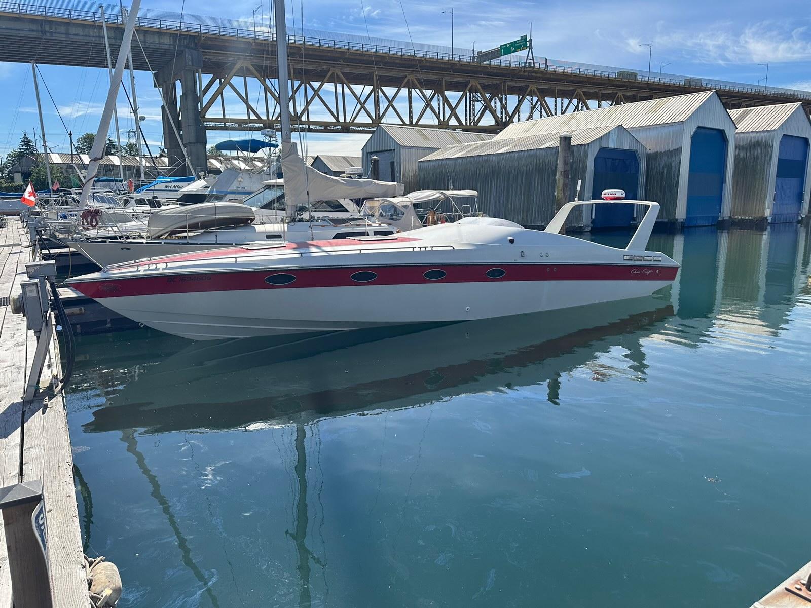 1988 Chris-Craft 375 boat docked in marina, under a bridge, with clear blue sky.