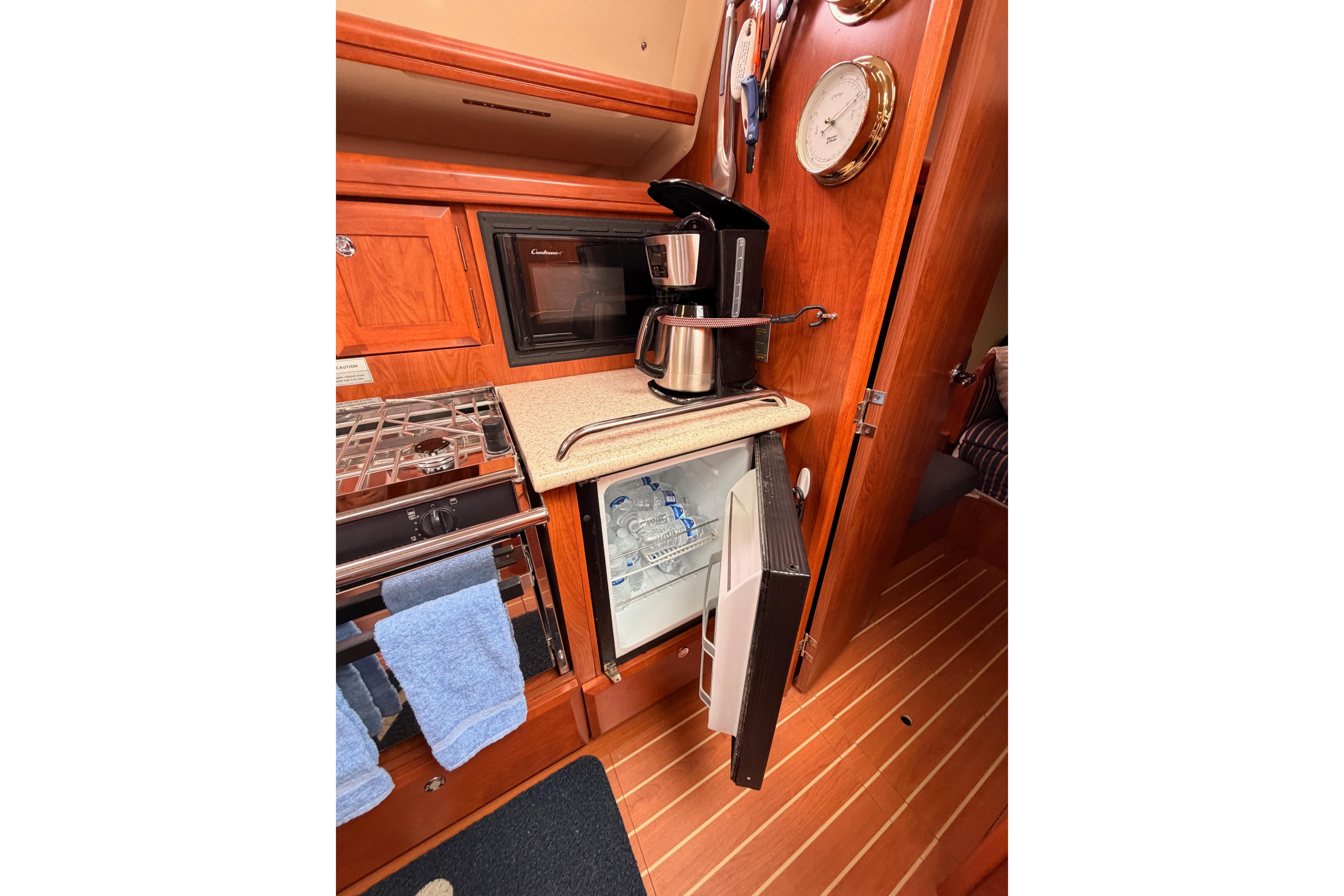 2009 Hunter 38 yacht kitchen with coffee maker, microwave, and open fridge.