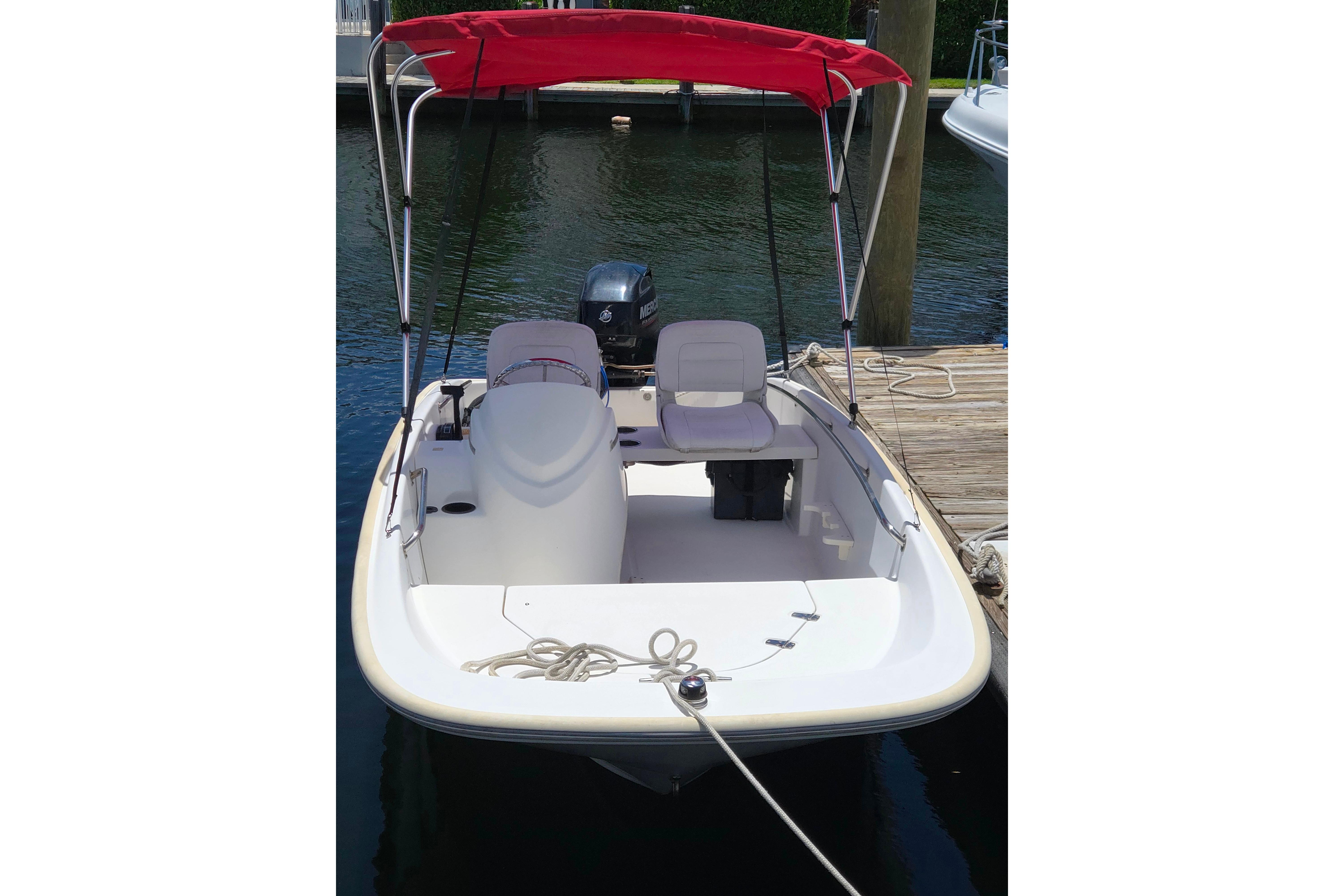 2014 Boston Whaler 13 SS boat with red canopy docked at marina.