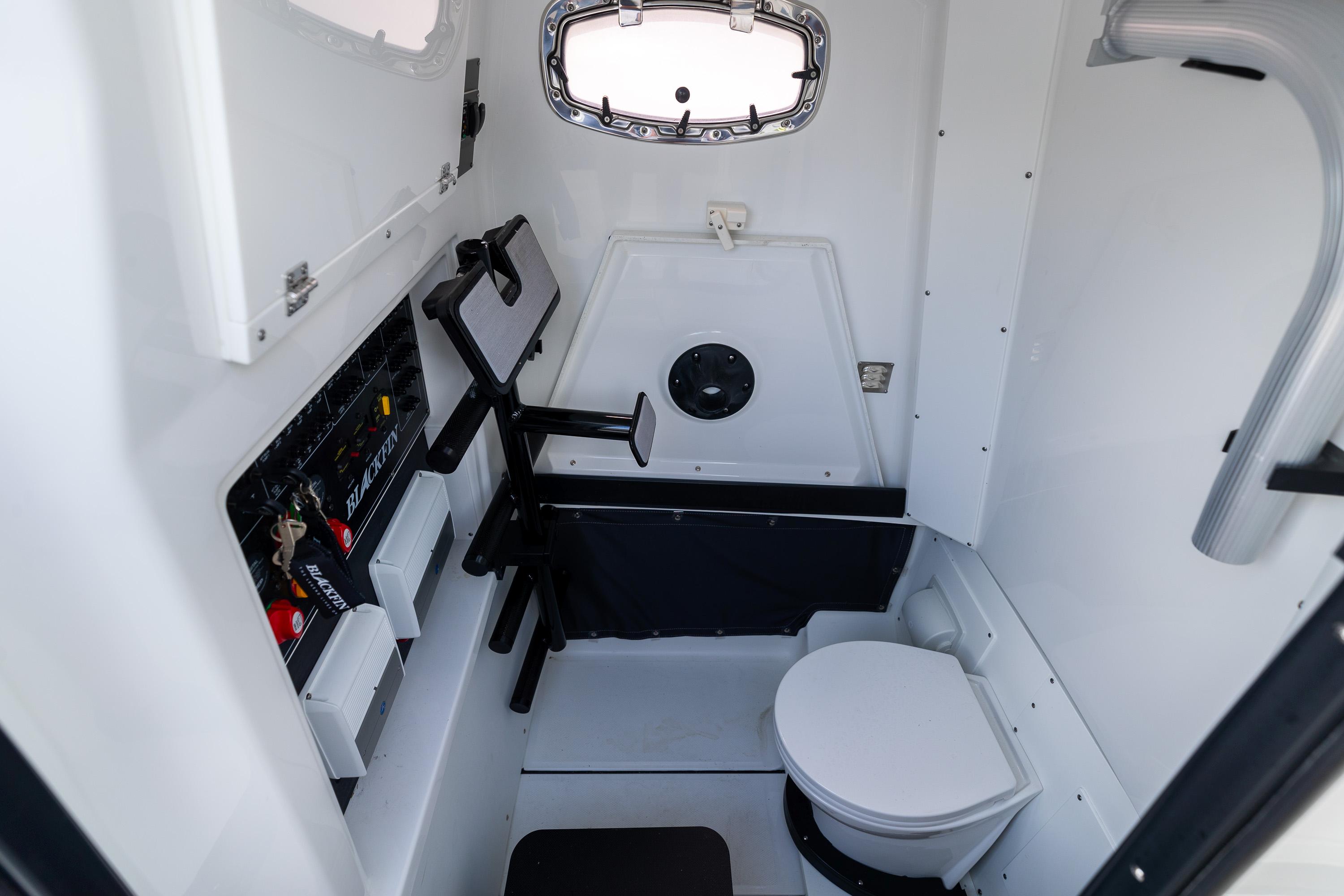 2023 Blackfin 302CC boat interior with compact bathroom and control panel.