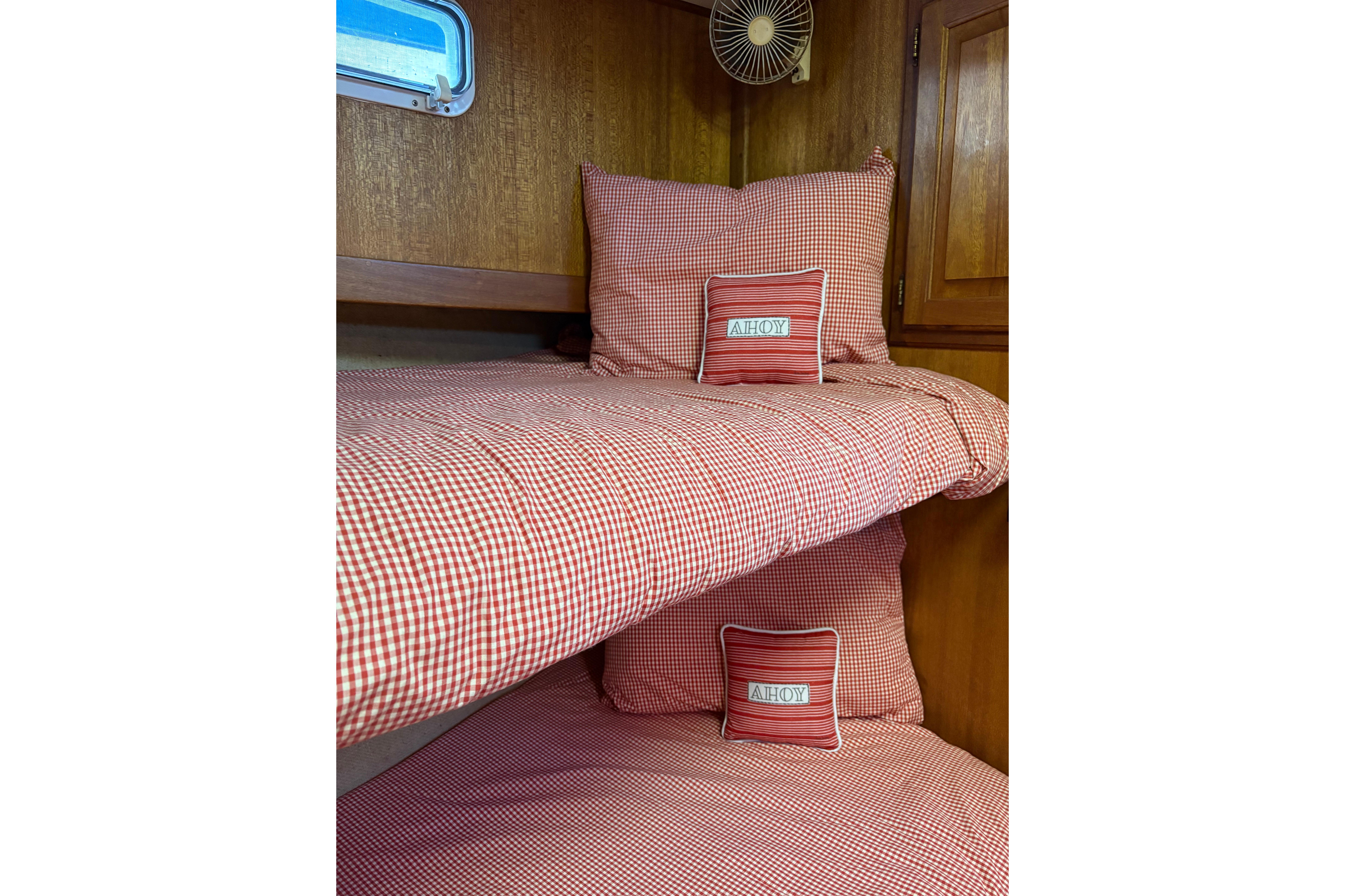 Cozy cabin bunk beds with red checkered bedding on a 1978 Californian 42 LRC boat.