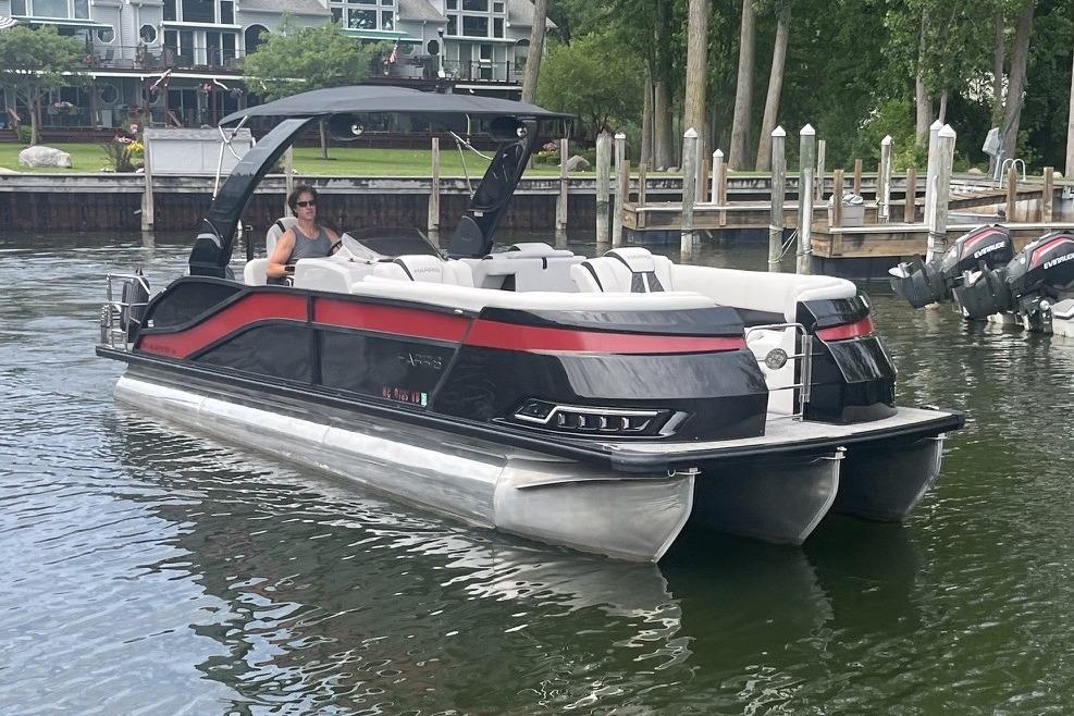 2024 Harris Grand Mariner 250 pontoon boat docked on a calm lake.