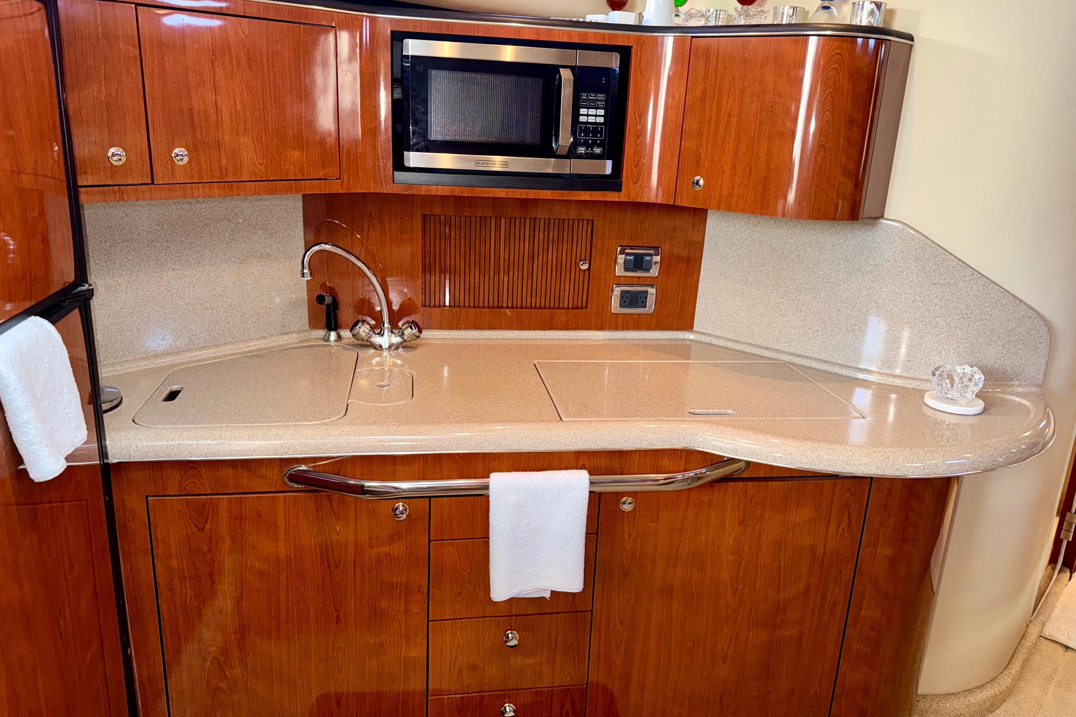 2003 Sea Ray 380 Sundancer galley with wood cabinetry, sink, and microwave.