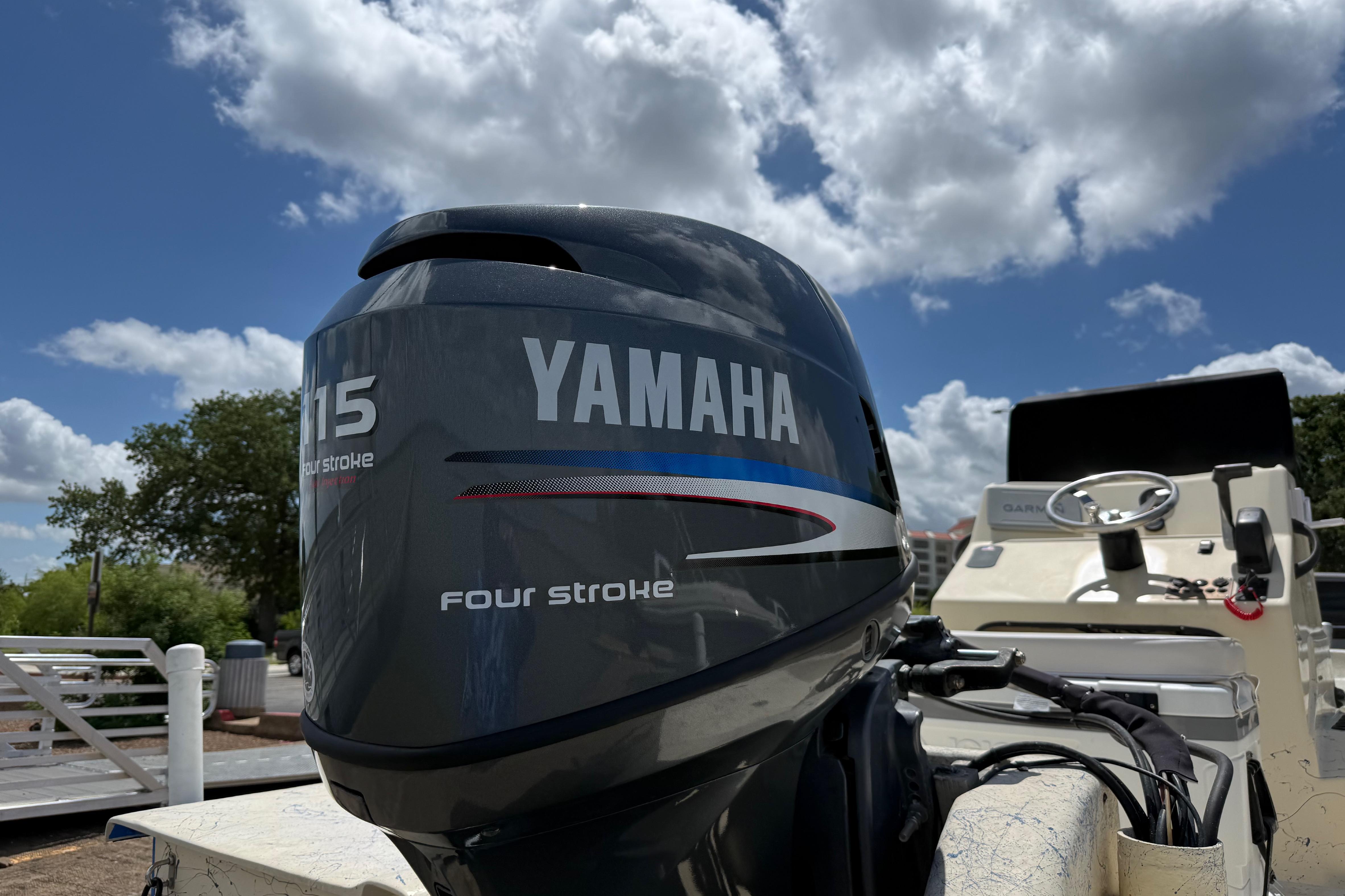 Yamaha 115 four-stroke outboard motor on 2007 Flats Cat 19 boat under blue sky.
