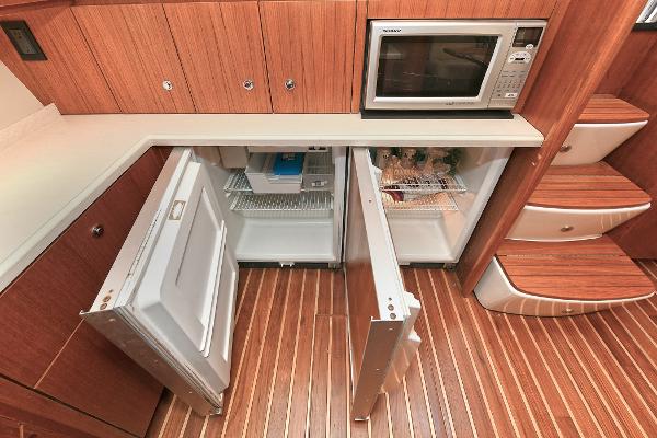 2008 Tiara Yachts 4200 Open galley with open fridge, microwave, and wooden flooring.