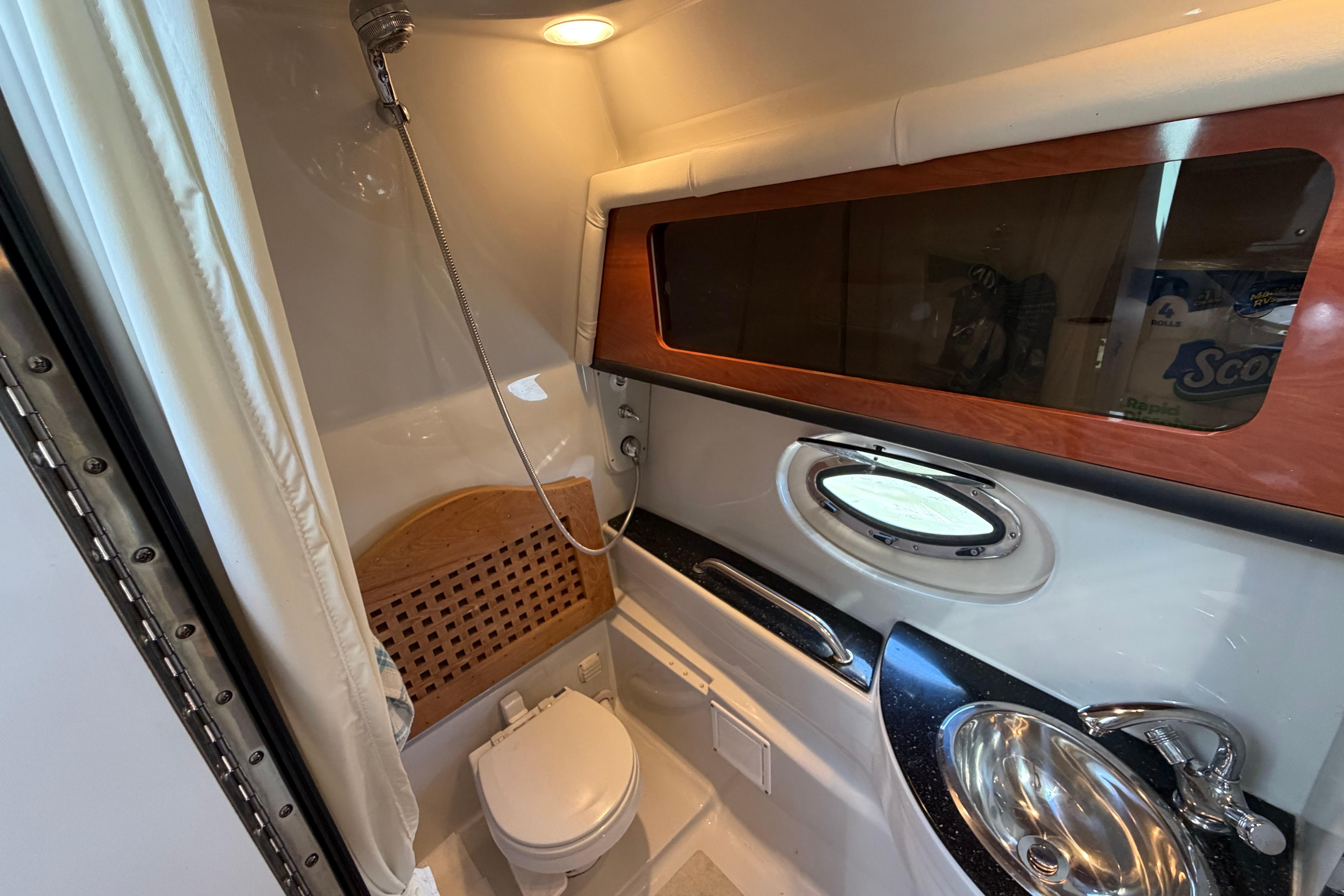 2008 Crownline 340 CR boat bathroom with shower, sink, and porthole window.