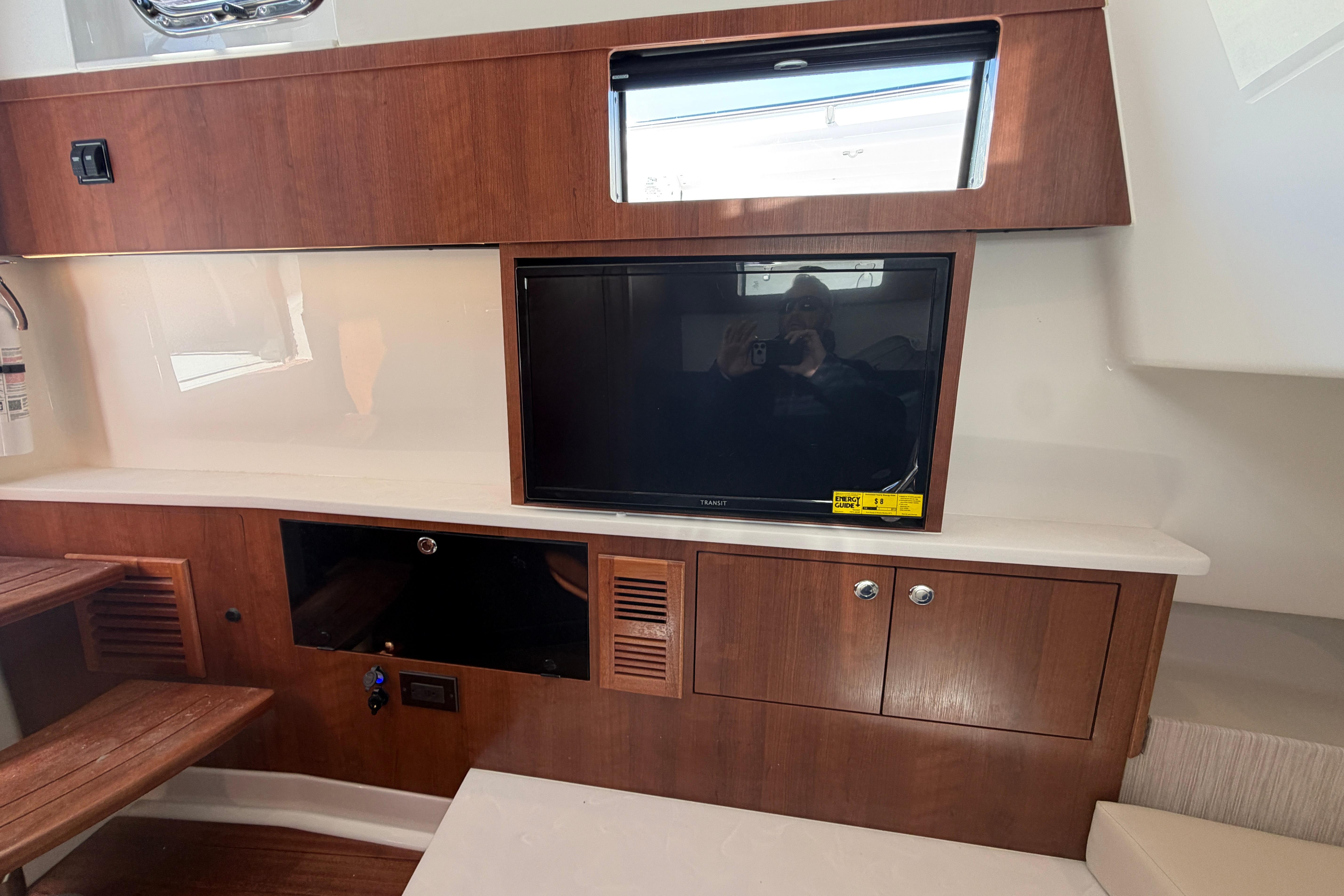 Interior of 2026 Pursuit S 358 Sport boat with wooden cabinetry and built-in TV.