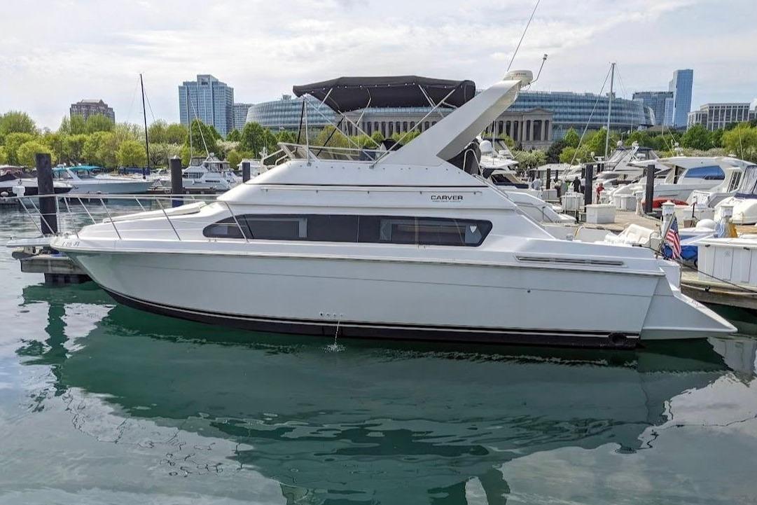 2002 Carver 380 Santego yacht docked in a marina with city skyline.