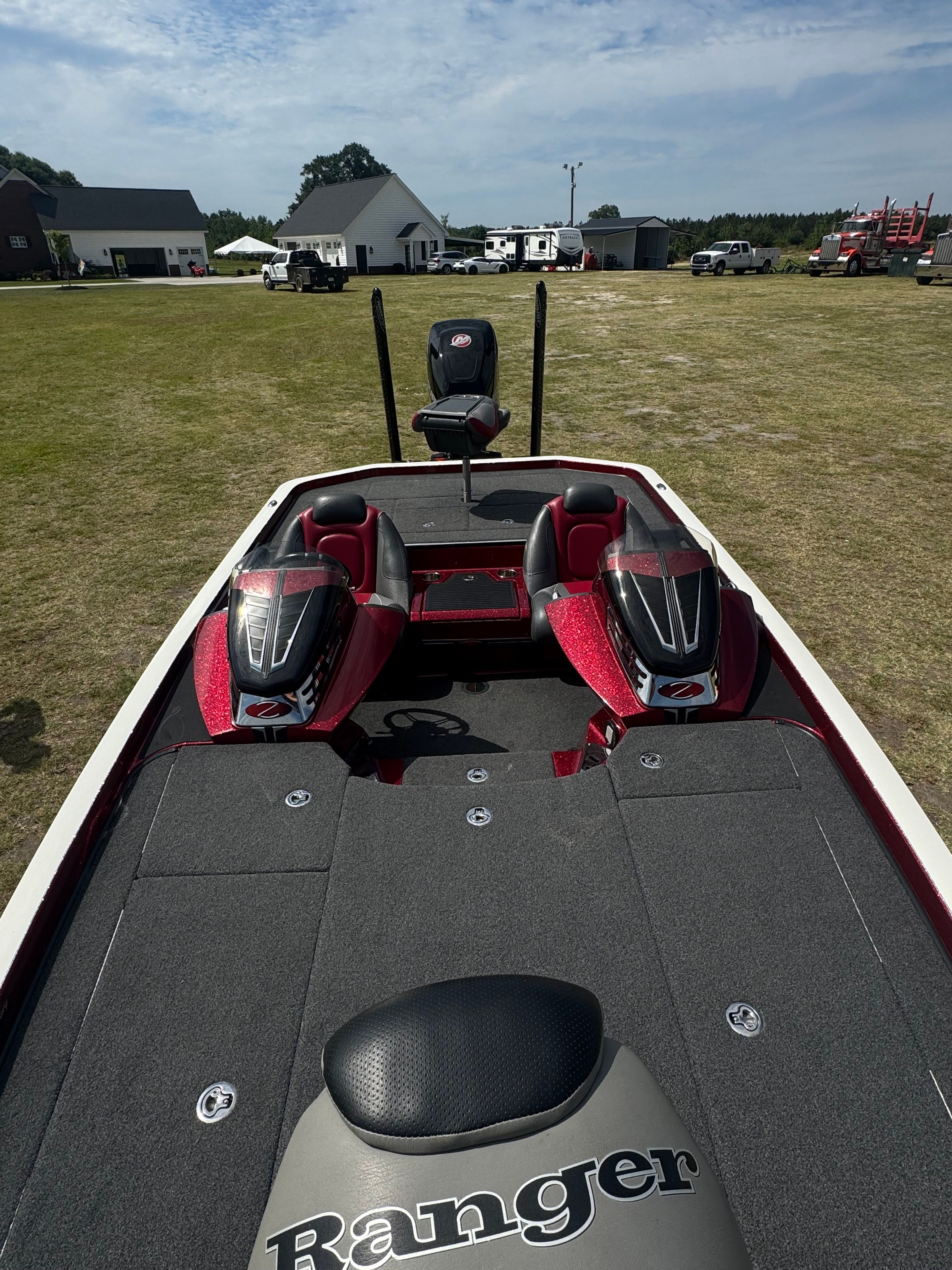 A Ranger boat is on a grassy field, surrounded by buildings and vehicles.
