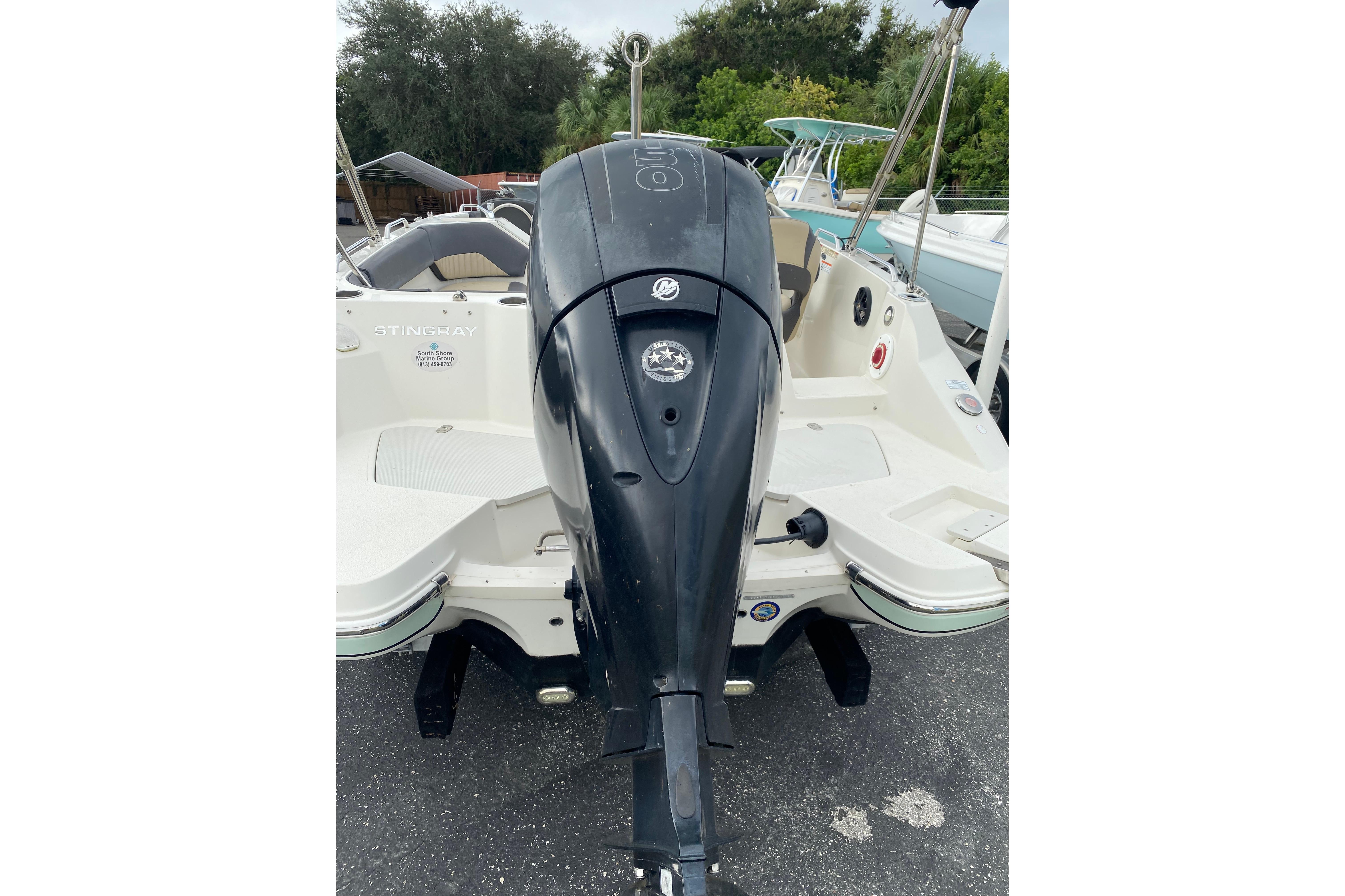 2018 Stingray 212 SC boat with outboard motor, parked on pavement.