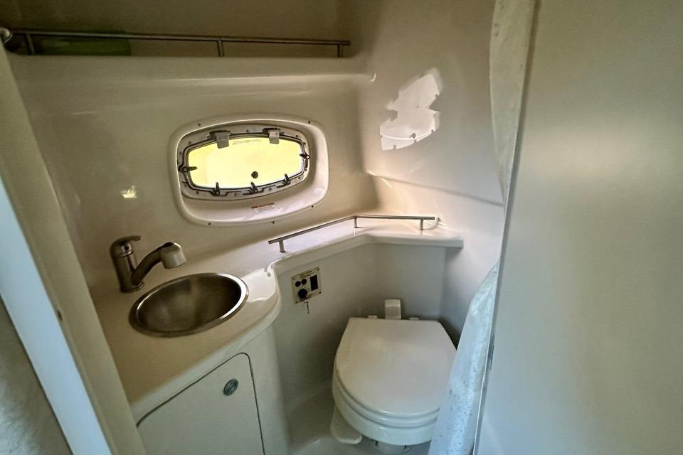 2013 Sea Ray 280 Sundancer bathroom with sink, toilet, and porthole window.