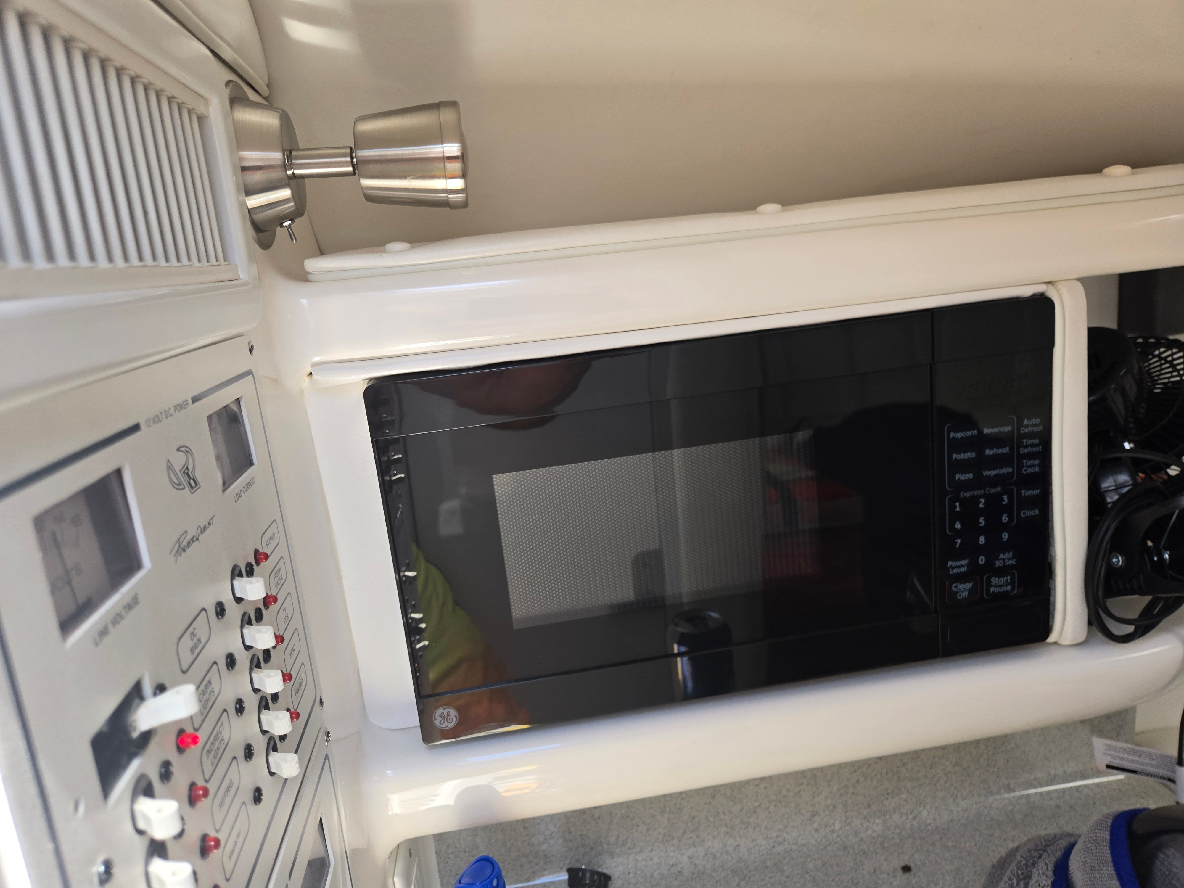 Interior of a boat with a microwave and control panel.