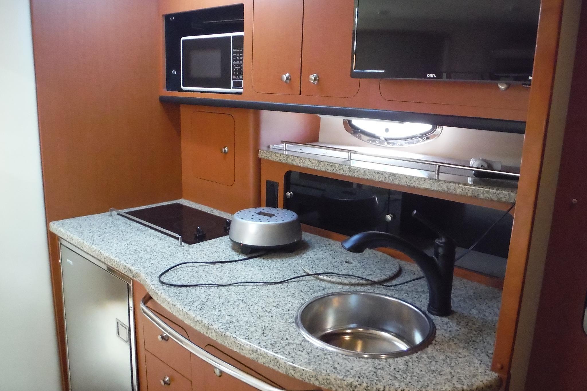 2005 Chaparral Signature 350 yacht kitchen with granite countertops, sink, and microwave.