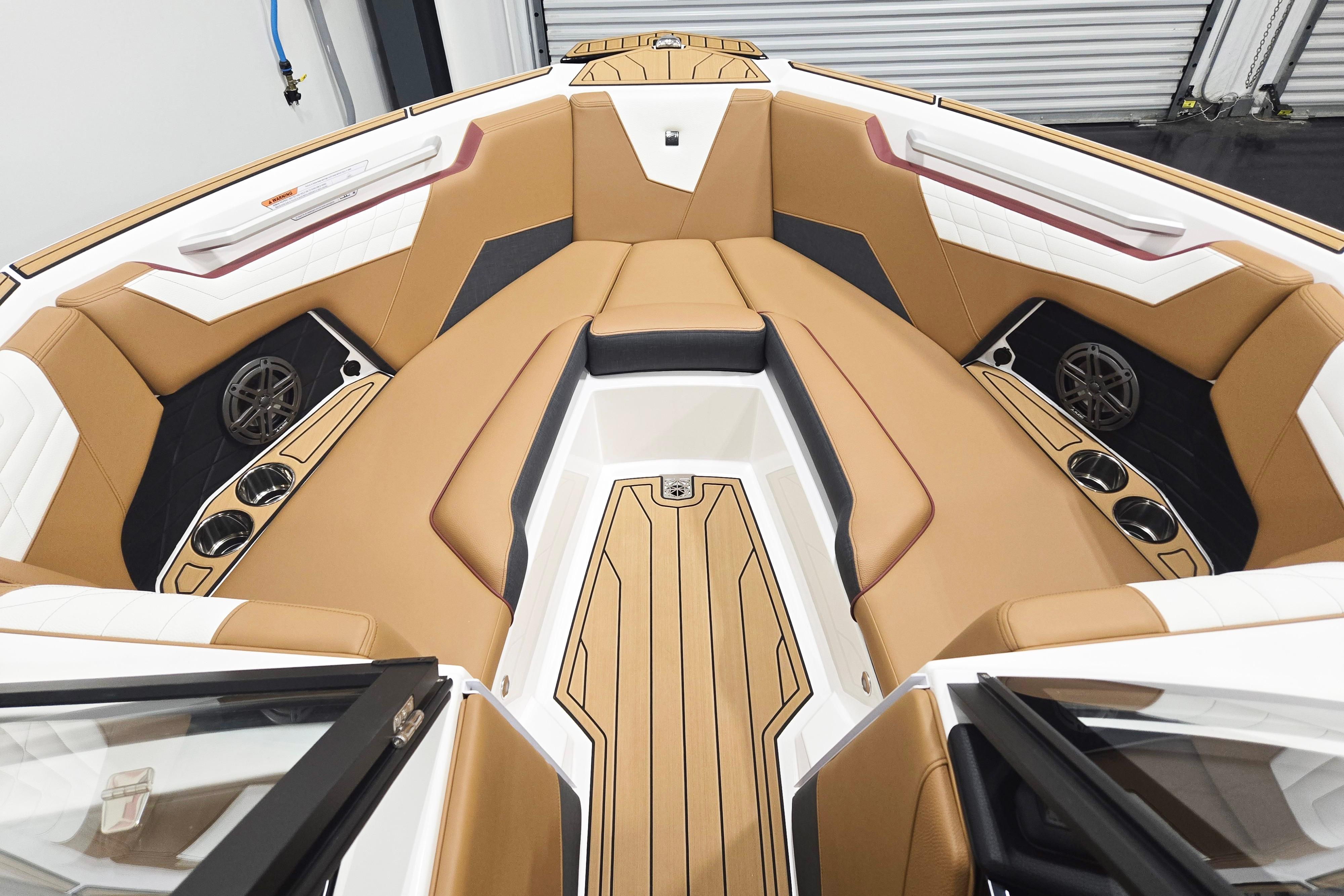 Luxurious interior of 2026 Nautique Super Air Nautique S23 boat with tan seating and cup holders.