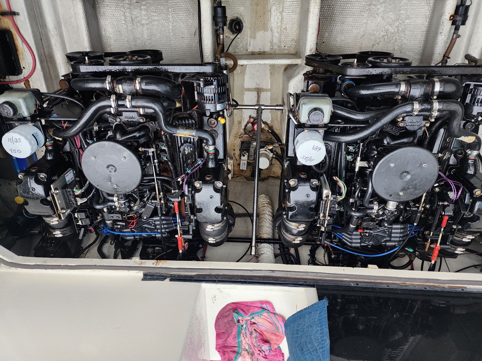 Two engines in a boat's engine compartment, clean and well-maintained, with some tools nearby.