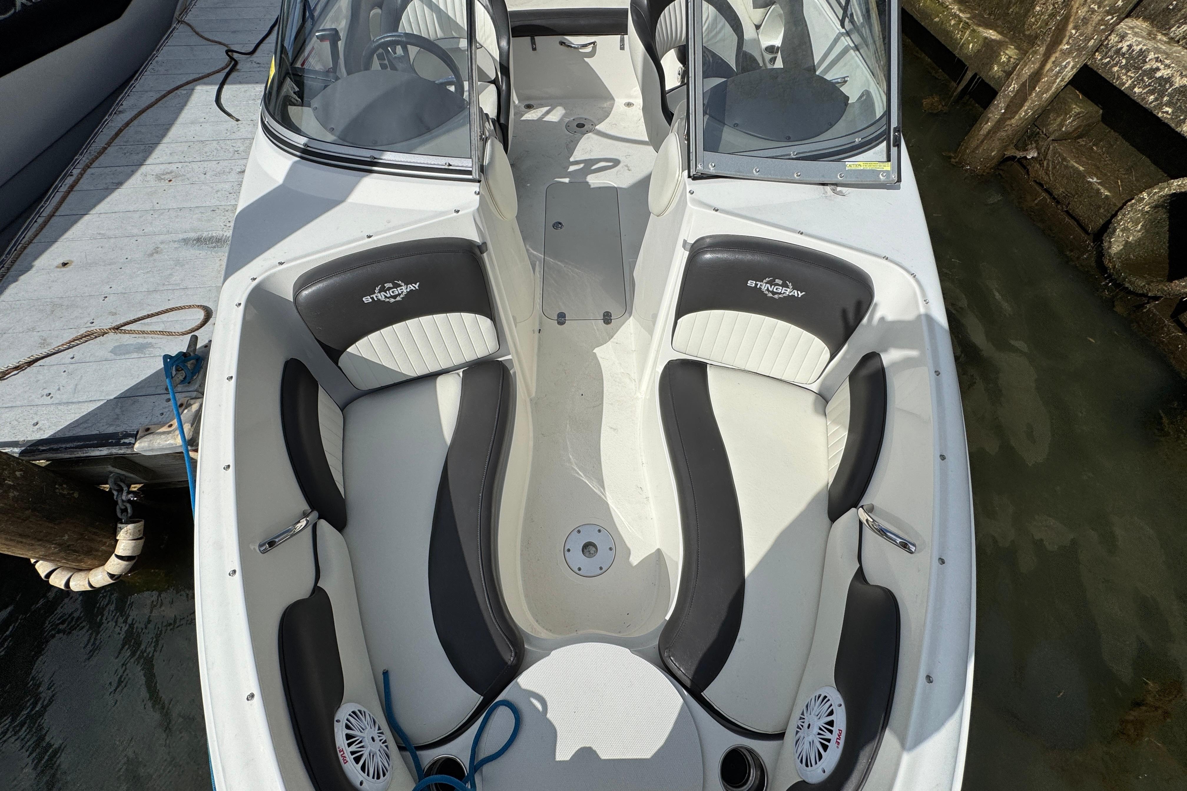 2019 Stingray 204 LR boat interior with white and black seating, docked by the water.